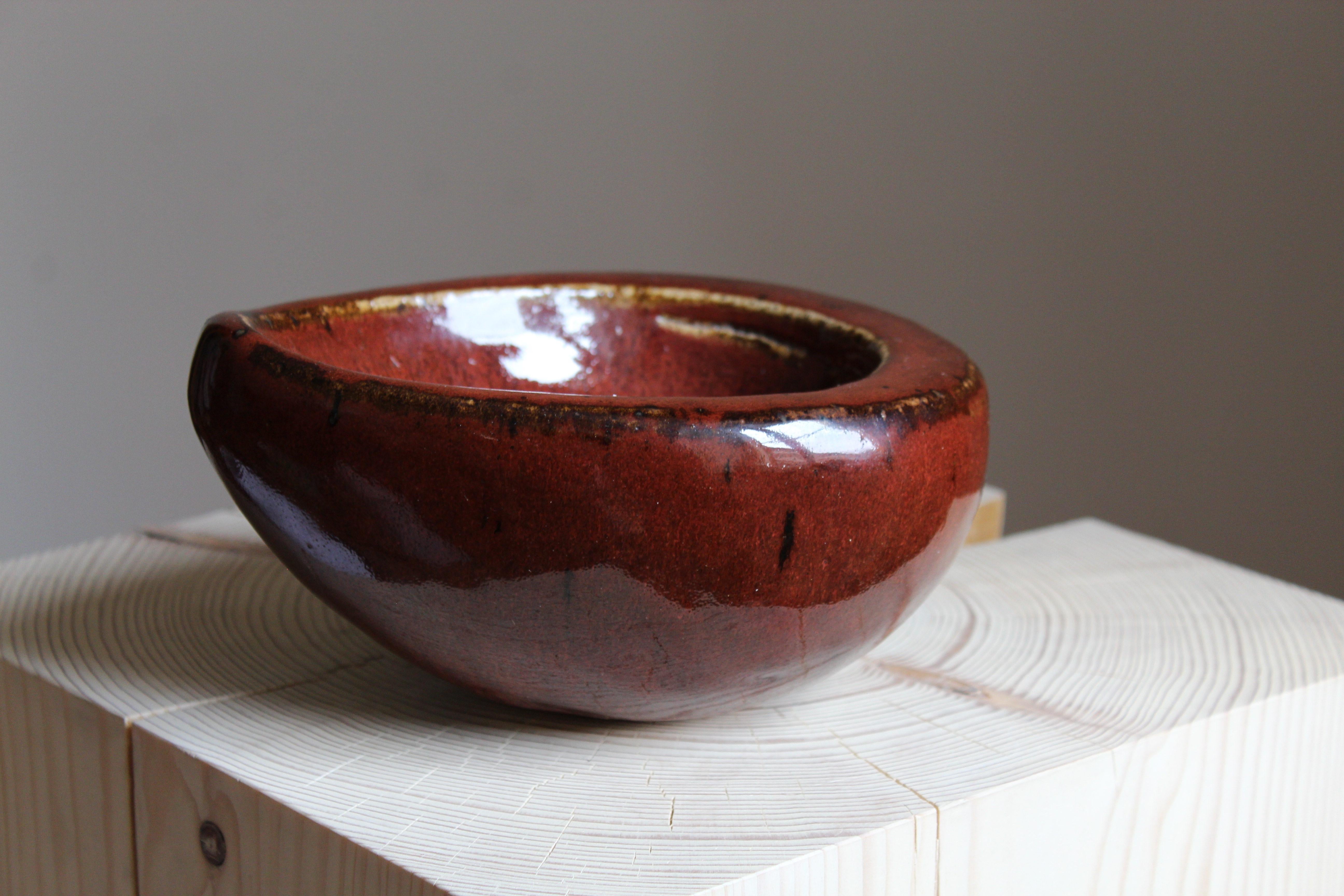 An organic bowl. Designed by Agnete Jørgensen for Bing & Grondahl, Denmark, 1960s. Stamped.

Features oxblood glazed stoneware. 

Other designers of the period include Axel Salto, Arne Bang, Carl-Harry Stålhane, Hans Cooper, and Lucie Rie.