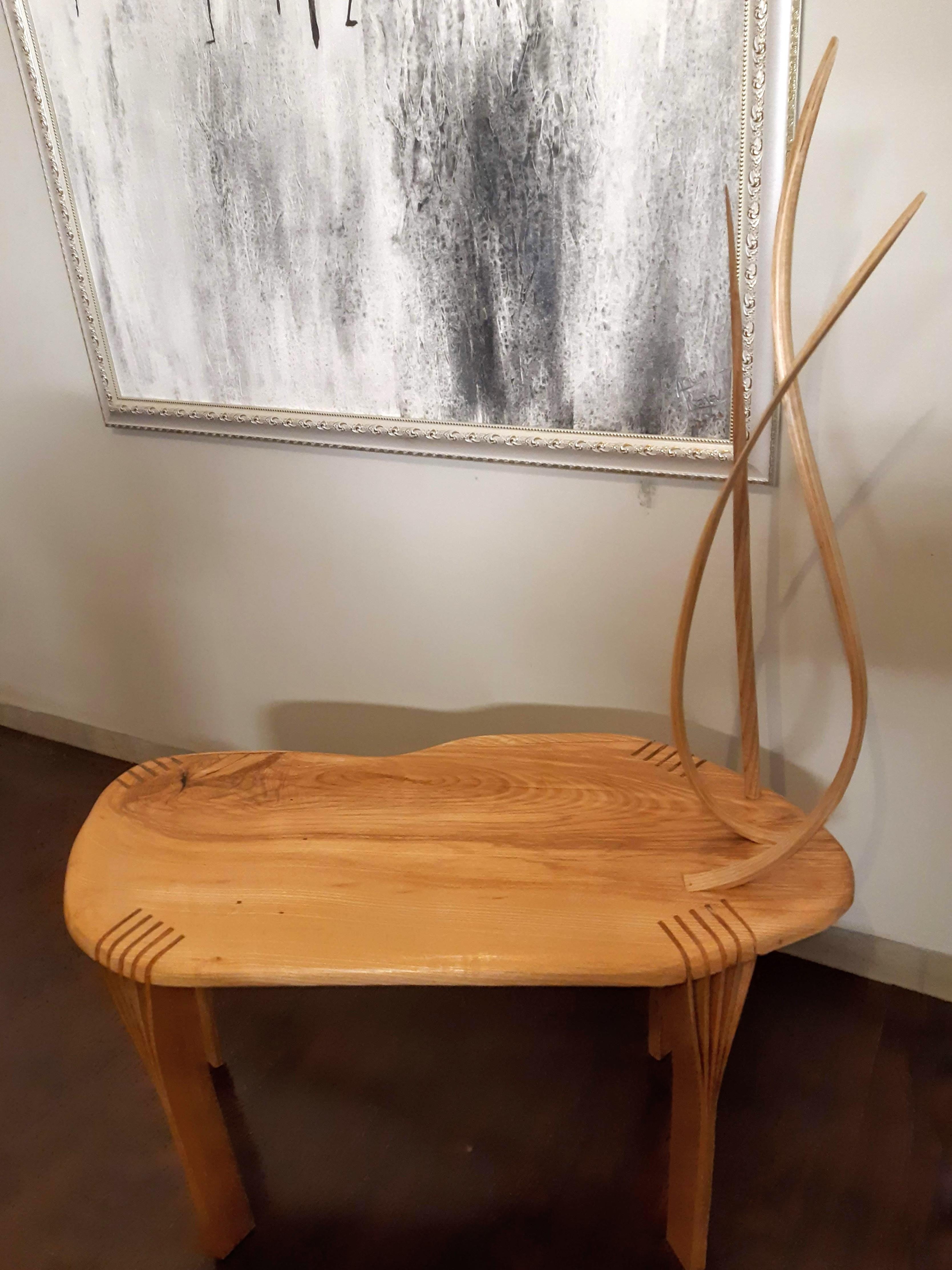 This piece is the Side Table No. 5 from the Vrksa Series.

The table is made using solid ash wood and it features vertically shaped strips of wood that have been bent and then carved to give them a smooth natural flow. The legs for the piece are