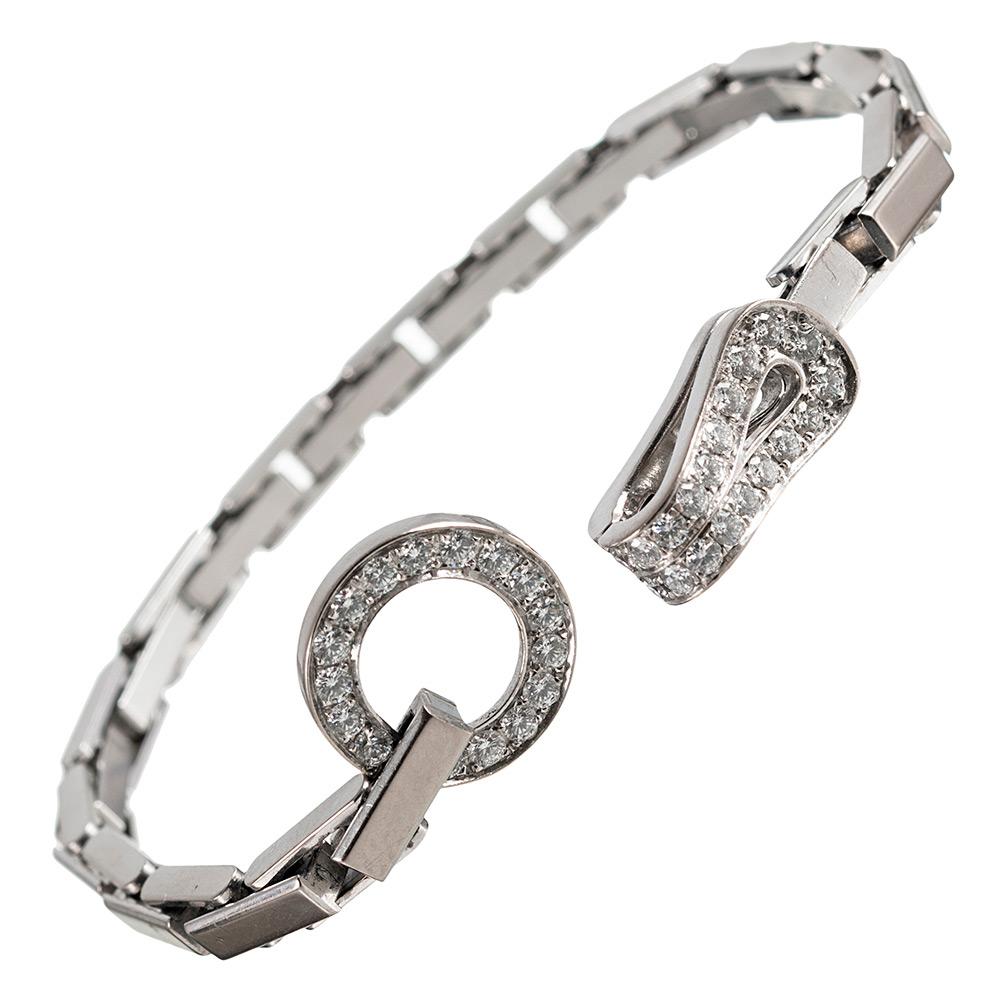 Cartier’s Agrafe Collection is centered upon its unique clasp, consisting of a circle and hook embellished with diamonds. This piece is no longer in production and is created of 18 karat white gold rectangular links with a clasp set with brilliant