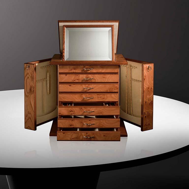 Jewelry chest in briar and mahogany, matte finish, ultrasuede lining, 24 karats gold plated brass accessories. With necklace bars, lockable doors and 6 drawers. Adjustable mirror on top part.
  