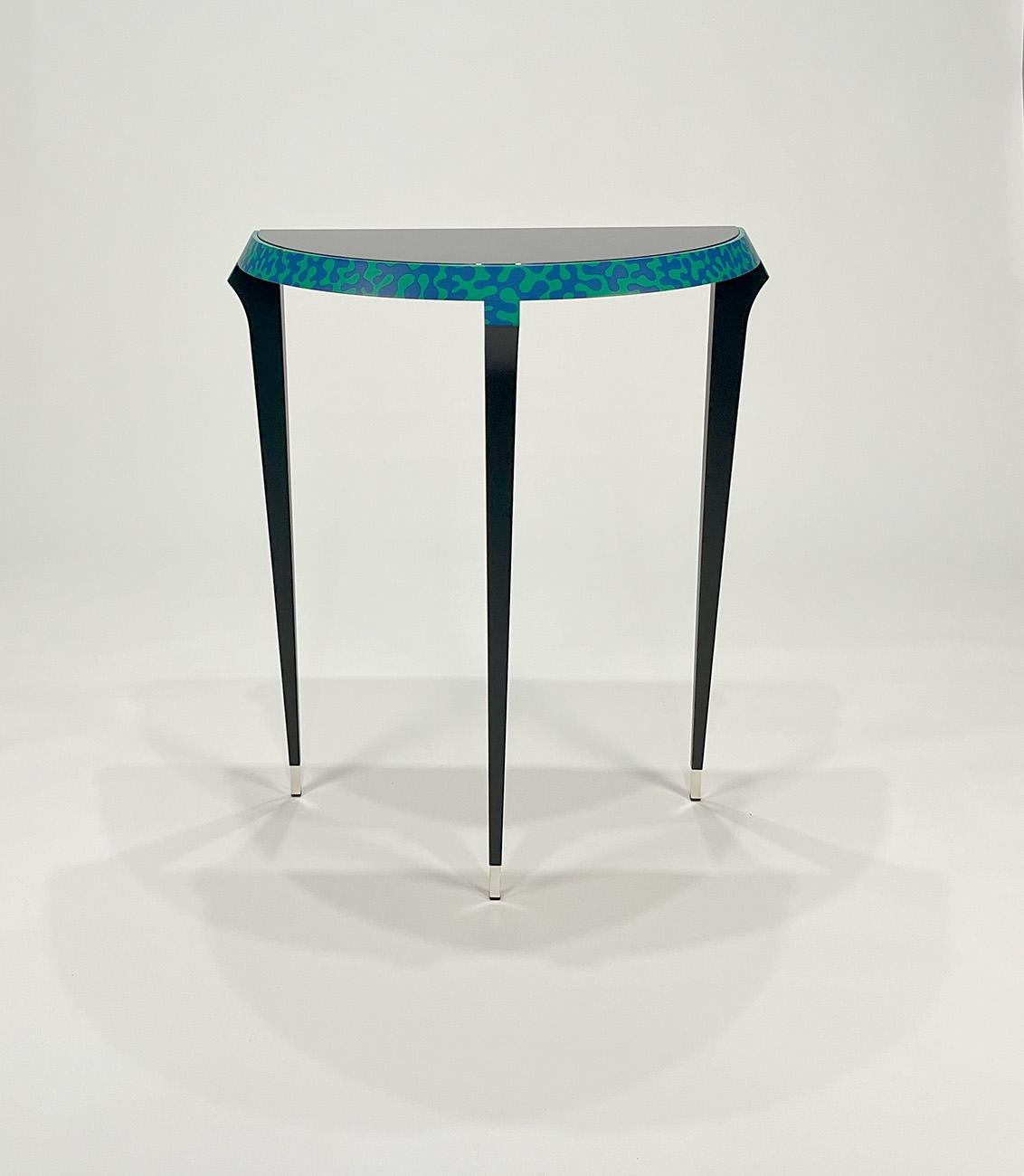 Table console Agrilo par Alessandro Mendini pour Zanotta Edizioni
1984
Mod. 7400
Original signé. Cadre en bois laqué noir. Bordure décorée à la main en bleu et vert. Pieds en laiton argenté. Dessus en verre plat peint en noir.