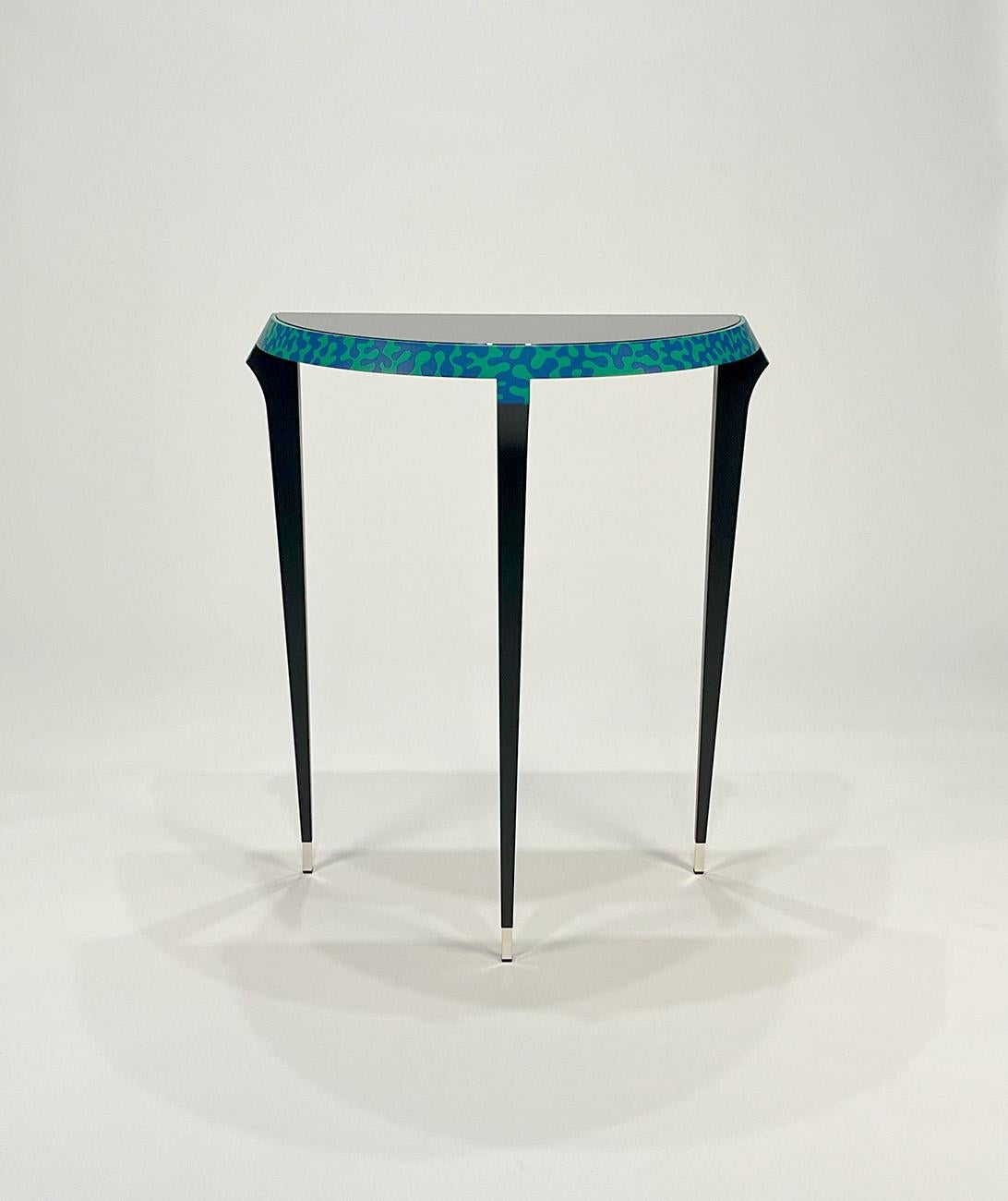 Table console Agrilo par Alessandro Mendini pour Zanotta Edizioni
1984
Mod. 7400
Original signé. Cadre en bois laqué noir. Bordure décorée à la main en bleu et vert. Pieds en laiton argenté. Dessus en verre plat peint en noir.