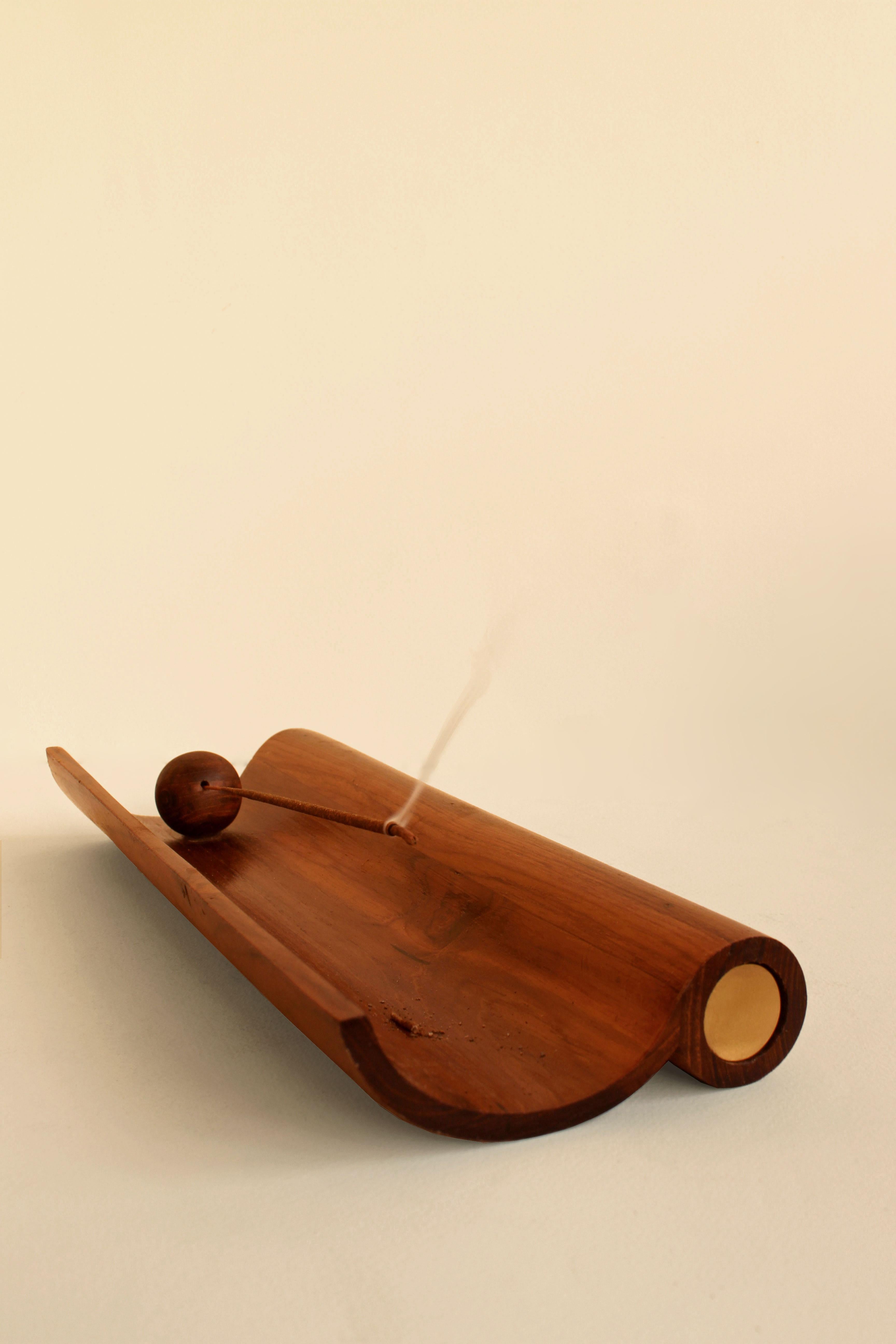 Aguru Incense Stick Holder by Studio Indigene
Dimensions: D 27.94 x W 11.43 x H 3.81 cm
Materials: Reclaimed Teak Wood, Brass.
Colors Brown, Natural Wooden, Brass Finish. 

Aguru elegantly holds an incense stick, and its brass casing slides out to