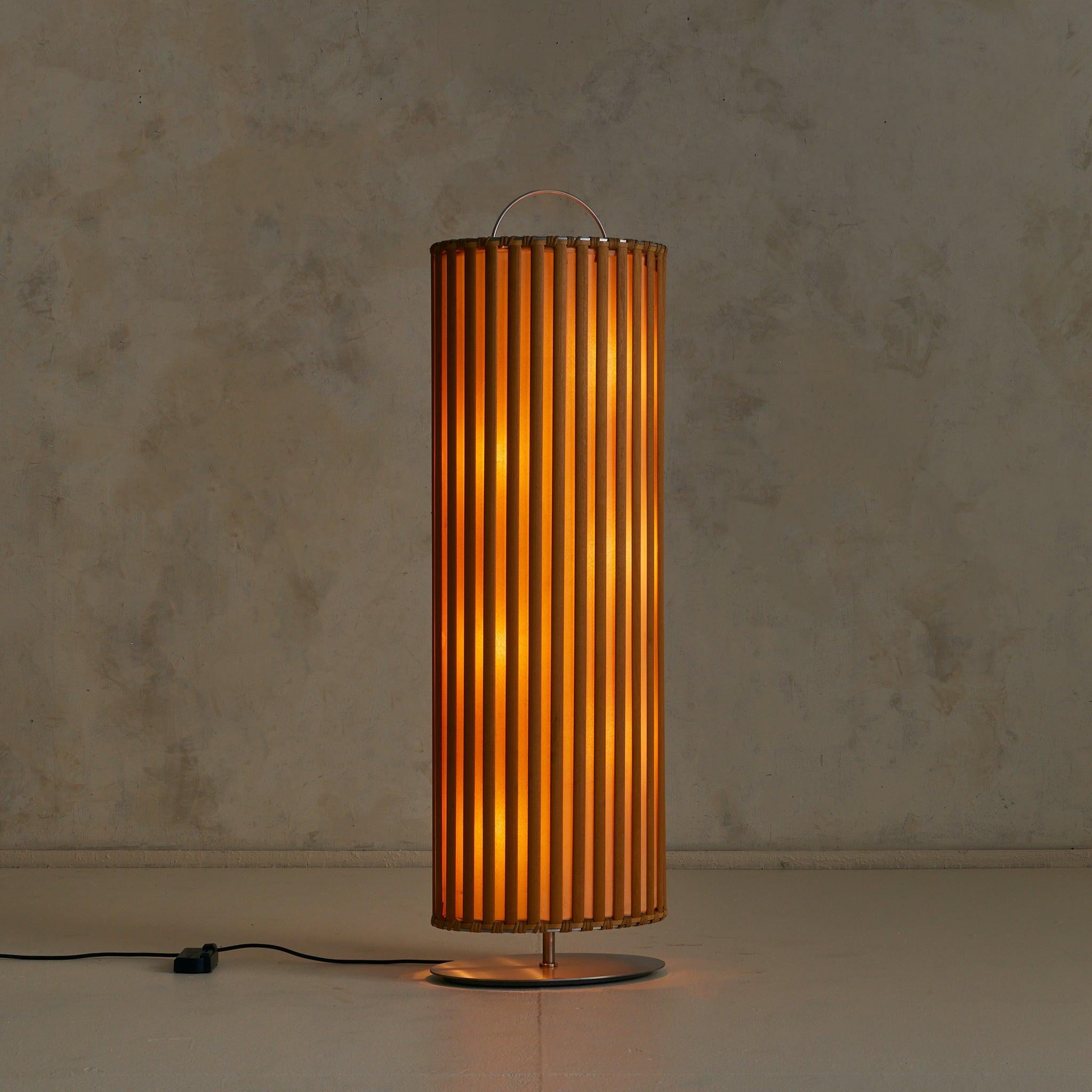 A rare ‘Aia’ floor lamp designed by Toshiyuki Kita for Sawaya 
Moroni in 2002. Standing over four feet tall, the cylindrical form is composed of vertical wood slats framing panels of delicate shoji-like paper, anchored by a metal base. When