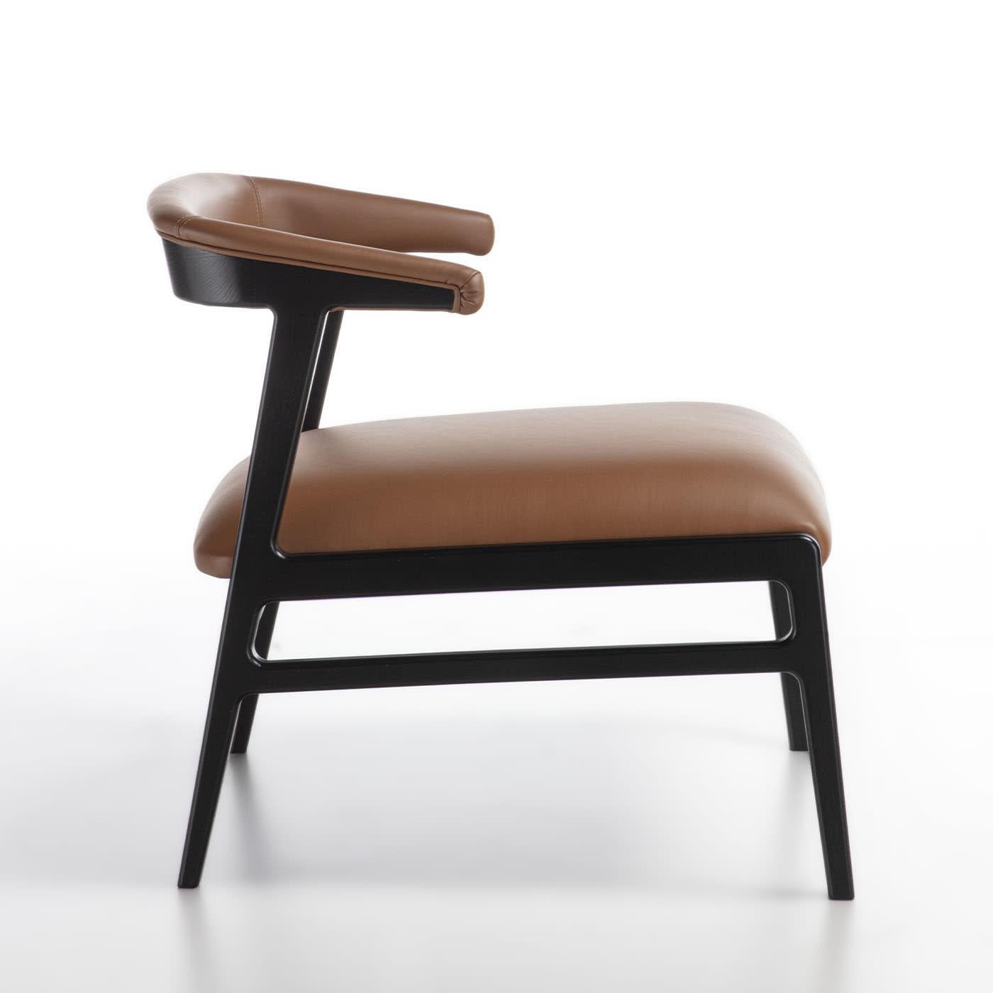 Lounge chair from the Aida line with an essential and light design. Structure in solid wood, upholstered back with an enveloping shape characterized by fine stitching. Seat and back upholstered in brown leather.