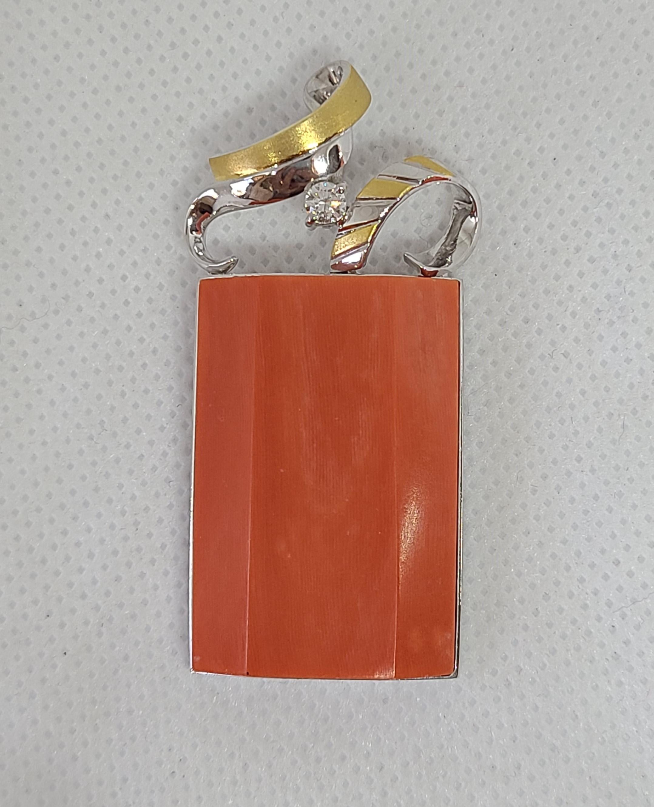 Ce corail naturel de couleur rougeâtre, sculpté dans une forme rectangulaire irrégulière, mesure environ 32,7 x 21,7 x 6,6 mm et pèse environ 33,26 carats. Le corail est serti dans une monture testée en or jaune et blanc 14K, rehaussée d'un seul