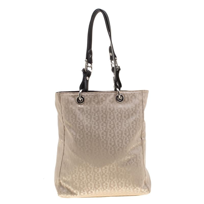 Stylish and trendy, this tote from Aigner is perfect for the fashionable you! The beige tote is crafted from signature fabric and enhanced with leather trims. It flaunts dual handles and zip pocket on the front. This tote will easily store all your