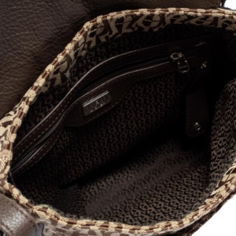 Charm your way through every gathering by swinging this flap bag from Aigner. Crafted from signature coated canvas and leather, the bag comes with a flap that has the brand label plaque. It carries a spacious interior that will easily hold all your