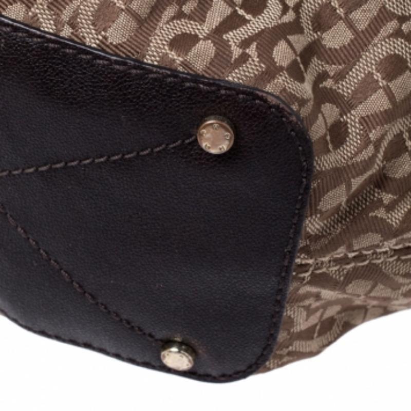 Be the talk of the town when you carry this Aigner handbag. Crafted with monogram coated canvas, this bag is styled with leather trims, drawstrings, and a single top handle. This chic bag has an equally divine interior lined with fabric. This beauty