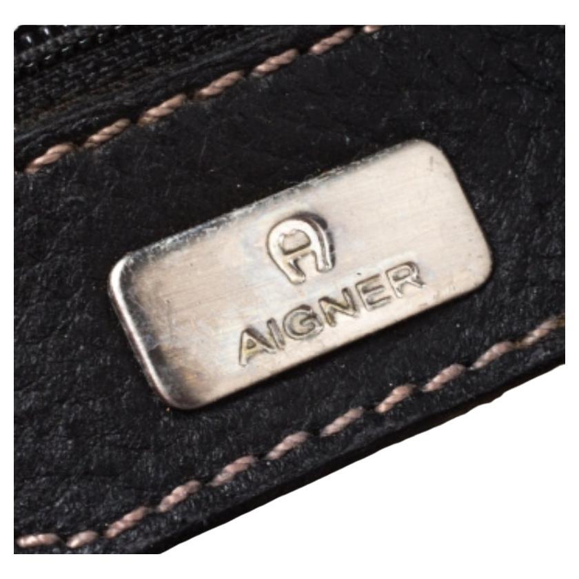This black satchel from Aigner will give you days of style and ease. It is crafted from leather and features a flap design. It is equipped with a well-lined canvas interior, two handles and silver-tone hardware.