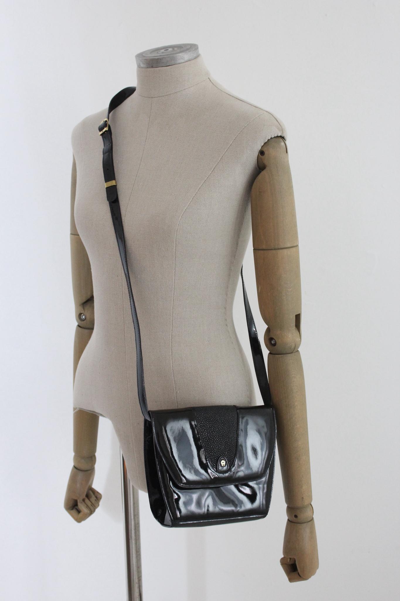 Etienne Aigner vintage 90s shoulder bag in patent leather. Black with gold details, trapeze shape, internally in velvet. Adjustable shoulder strap, clip button closure. Bag that can be used for any event from the coolest to casual occasions. Made in