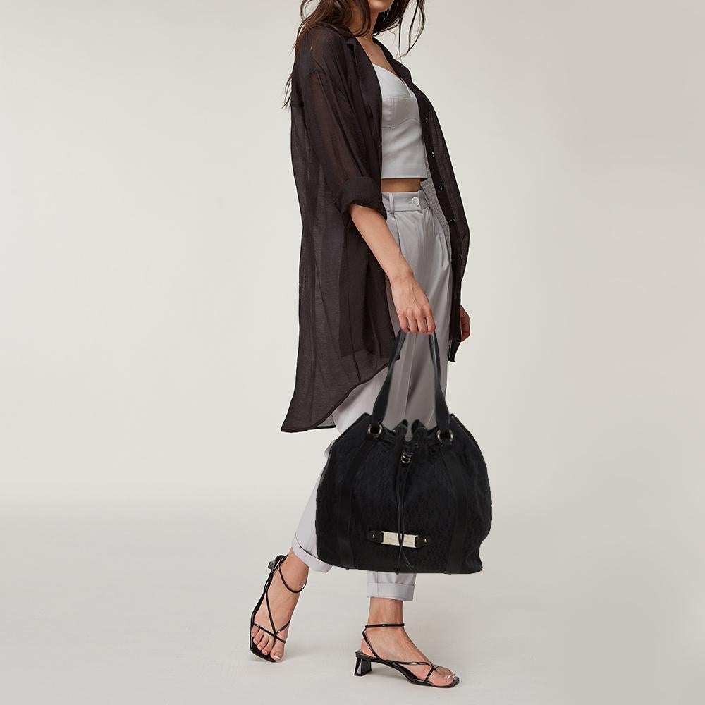 This lovely bag hails from the house of Aigner. It has been crafted from signature-coated canvas and leather and carries a lovely shade of black. It has a drawstring closure, top handles, silver-tone hardware, and a spacious fabric-lined interior.