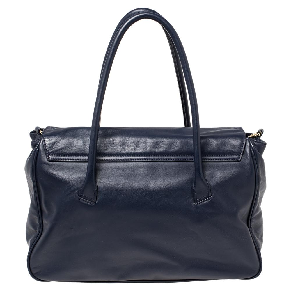 This blue satchel from Aigner will give you style and ease. It is crafted from leather and features a dangling logo charm. It is equipped with a spacious fabric interior, two handles, and gold-tone hardware. This bag is chic, practical and will keep