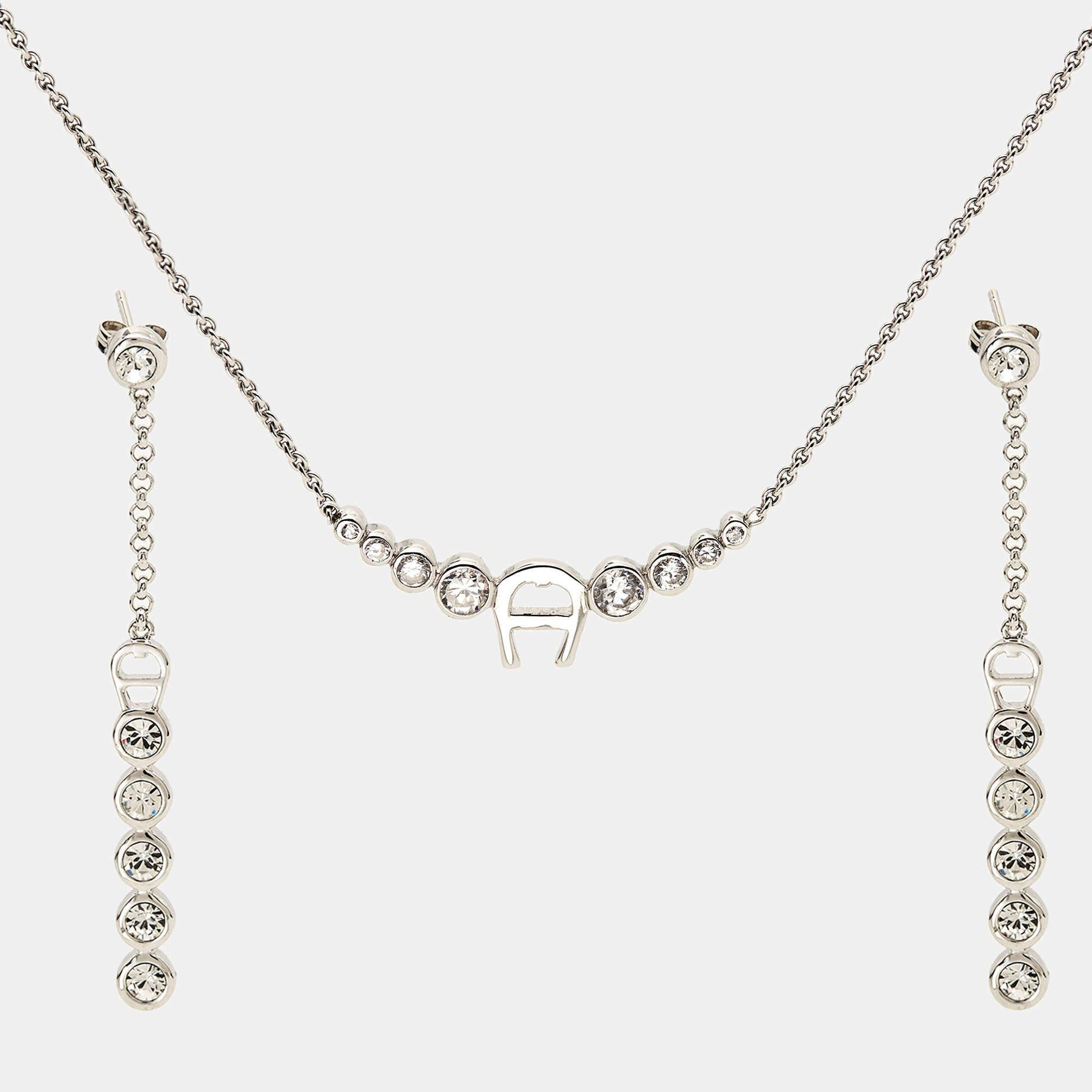 This delicate set from Aigner is made of silver and ornamented with crystals. The necklace and earrings feature a lovely design highlighted with the brand logo. The set is simple, chic, and great for special events.

Includes: Original Case

