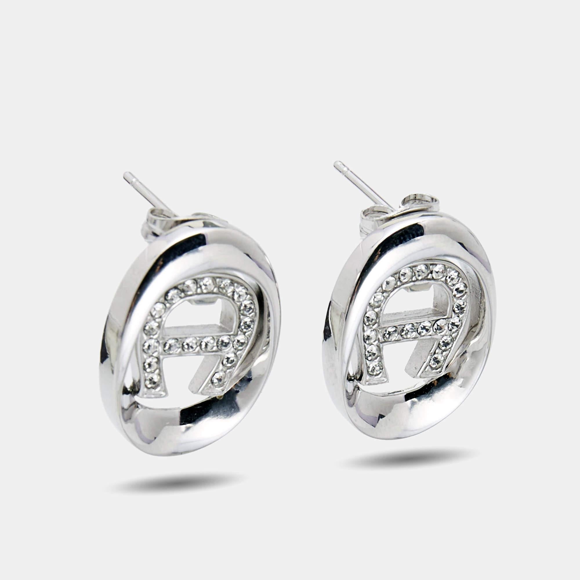 Dieses schlichte und elegante Paar Ohrringe von Aigner zeigt das Markenlogo in silberfarbenem Metall mit Kristallen. Das Paar verleiht jeder schicken Garderobe einen gewissen Charme.

Enthält: Original-Box, Original-Etui


