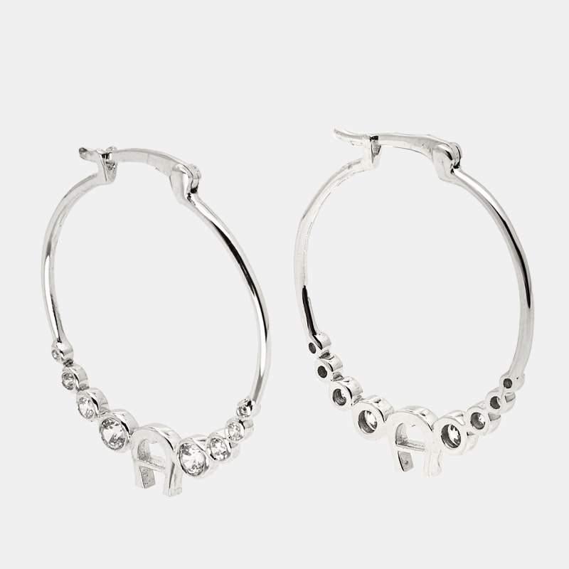 Designed with silver-tone metal, these hoop earrings from Aigner will complement a day or evening look. They feature the brand logo and crystals. Balance your outfits with this elegant pair.

Includes
Original Dustbag