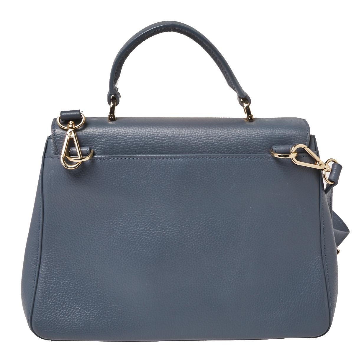 This Isabella bag from Aigner is crafted from grey leather and has a well-structured design. The bag comes with protective metal feet, a top handle, and a shoulder strap. The front flap opens to a fabric-lined interior capacious enough to carry your