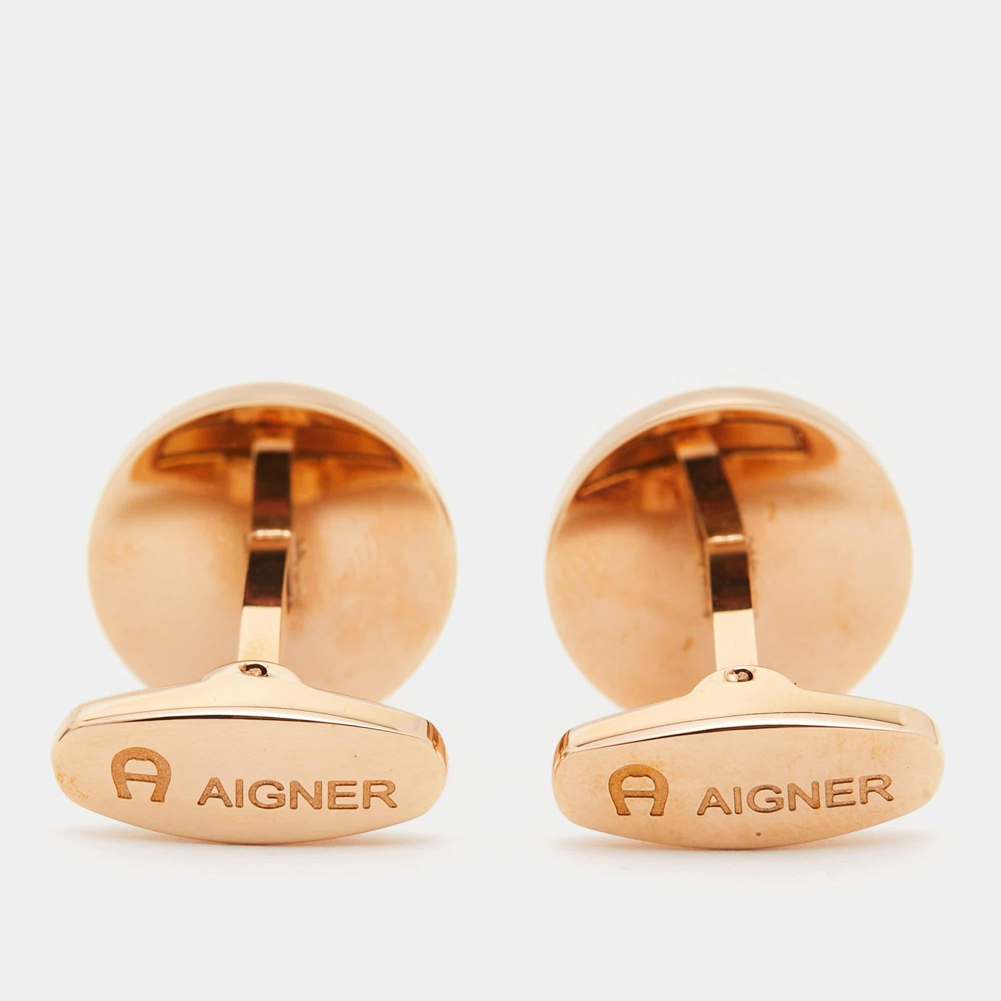 Aigner cufflinks exude sophistication with their refined design. Crafted in gold-tone metal, they feature enamel detailing, adding a touch of elegance. The iconic Aigner logo is subtly incorporated, making these cufflinks a stylish accessory for