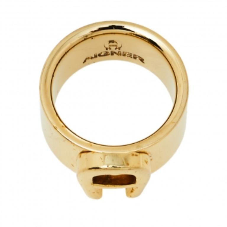 Make a stunning style statement as you head out wearing this Aigner ring. Featuring a gold-tone band silhouette, this ring is topped with a logo-detailed center. Wear it stacked with other sleek rings or as a stand-alone piece.
