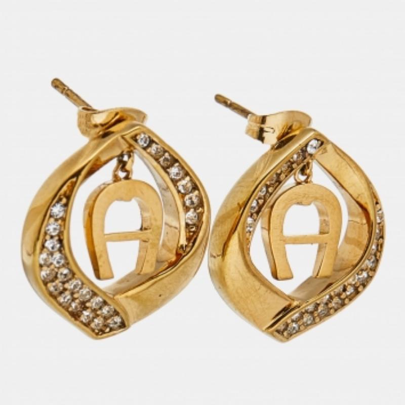 Complétez une tenue chic avec cette paire de boucles d'oreilles Aigner. Ce modèle à clous en métal doré est orné du logo de la marque et de cristaux.
