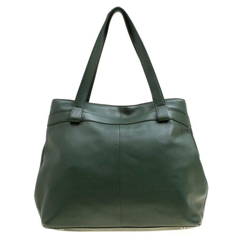Featuring two handles and a lovely green shade, this Aigner leather tote exudes just the right amount of sophistication. The bag features a capacious compartment to house all your essentials and on the front, it has a little bow and the logo. This
