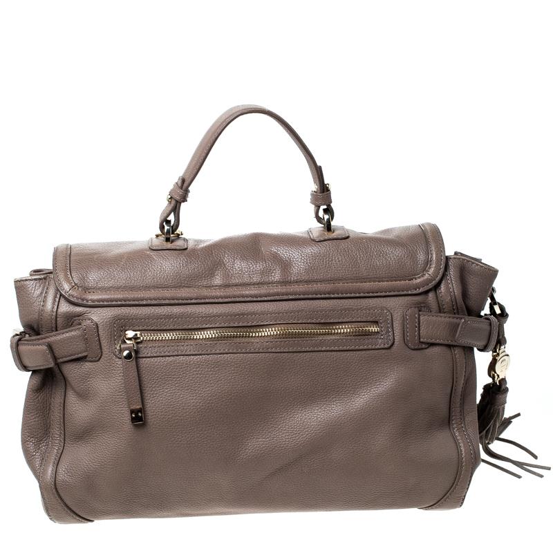High on style, carry this handbag from Aigner without compromising on style. This alluring leather bag is elegantly designed with a front flap, a top handle and a back zippered pocket. This pretty piece has a fabric-lined interior. Add a stylish
