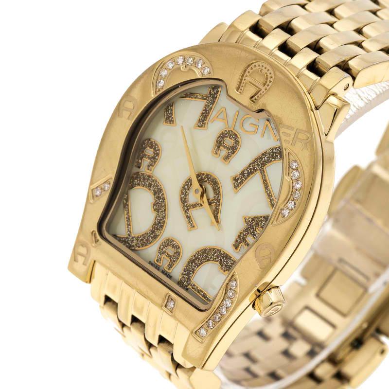 This Aigner Ravenna Nuovo watch is fashioned in a gold-plated stainless steel body with a case diameter of 33mm. It comes attached with the logo-shaped, mother of pearl dial with gold-tone hands and diamond-embedded detailing on the bezel. This