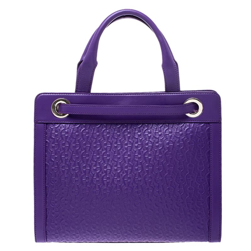 Designed to look nothing but flawless, this Cavallina bag from Aigner is a dream you can add to your collection! Fabulous in purple, it comes crafted from logo-embossed leather and features dual top handles. It flaunts a strap looped around like a