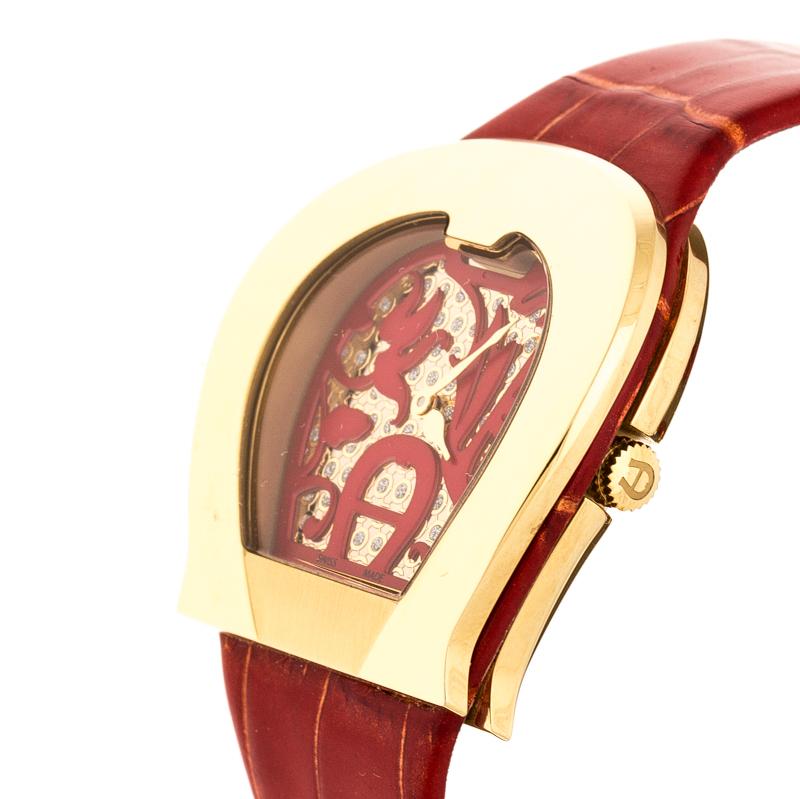 Aigner's 'L'Aquila' women's wristwatch features a uniquely designed dial & bezel. The dial is detailed with an intriguing design, stud embellishments and two hands. It comes with a red leather strap secured by a buckle closure. Add a glamorous touch