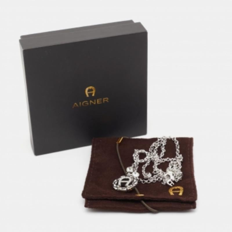 Beautifully crafted from silver-tone metal, this Aigner necklace is added with the brand logo and crystals. The pendant is held by a chain and is complete with a lobster clasp. This minimal creation will surely light up your neck.