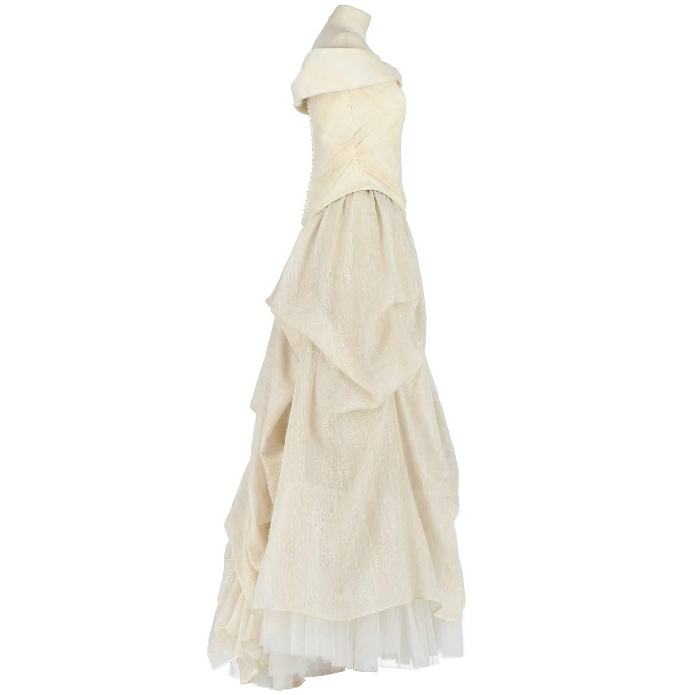 Princess dress Emé by Atelier Aimée in ivory withe-beige blend linen fabric. It features two pieces, one off-the-shoulders neckline top with slats and beautiful draped skirt with two layers of tulle veil and a petticoat. Zip and pearls buttons