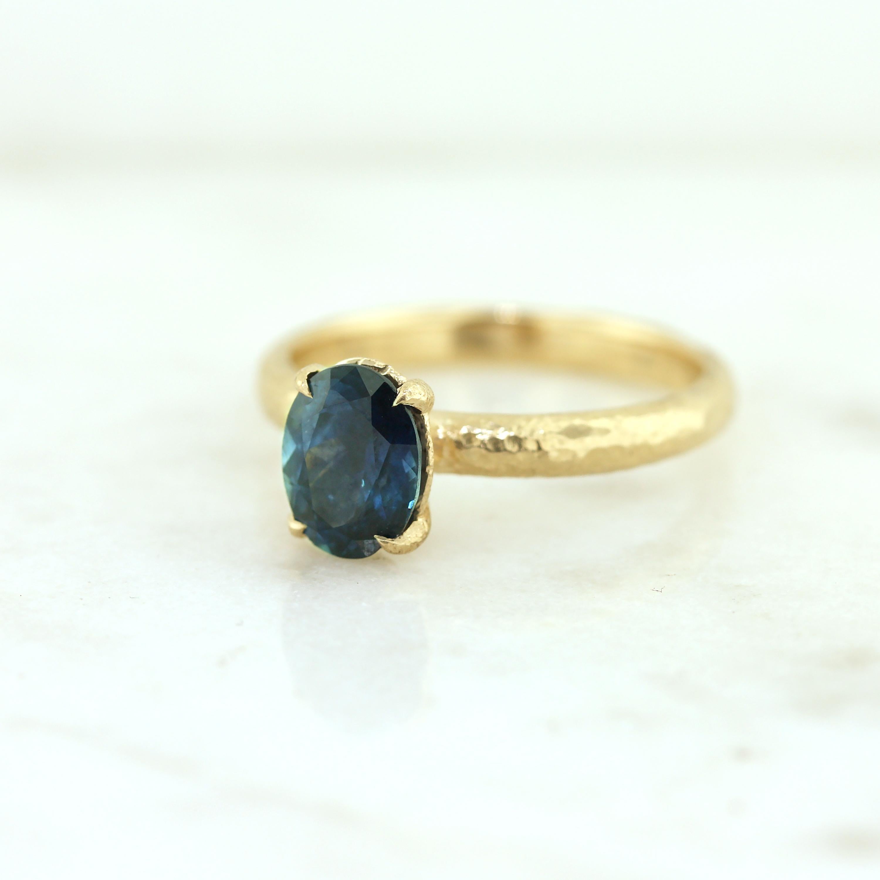 Rustic solitaire ring with signature hammered texture and a 1.93 carat deep blue Montana sapphire set in 100% recycled gold. This size and colour are rare in sapphires sourced from Montana. 
One of a kind.

- Finger size 6.25
- Available for