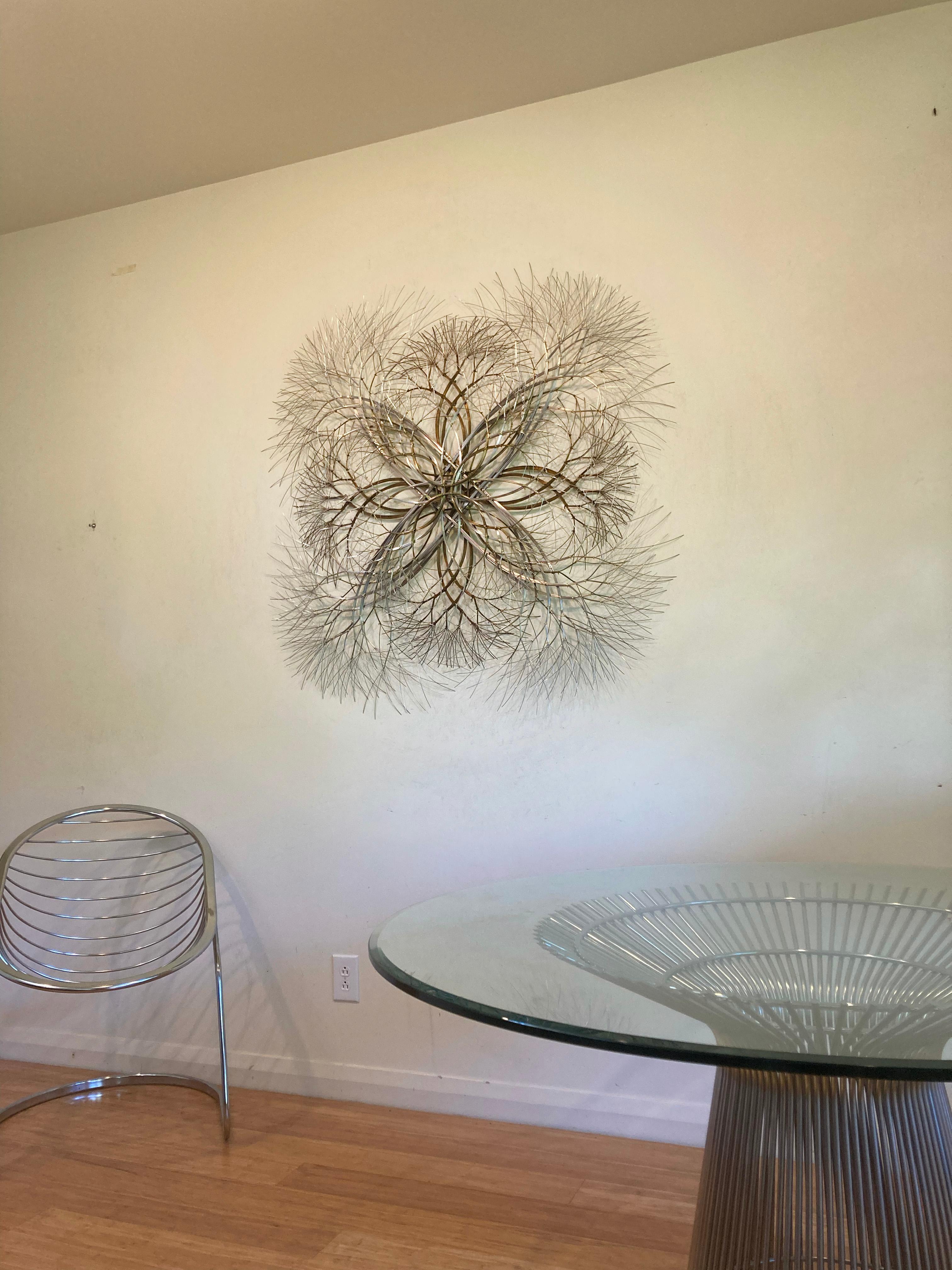 This mirrored geometric sculpture is by Kue King and created using brass and stainless steel wire. Kue uses an aesthetic reminiscent of trees, electricity, and light to create sculptures of peace and beauty. Adults and children alike see snowflakes,