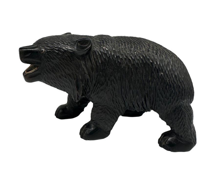 Eine traditionelle Ainu-Bärenschnitzerei stellt typischerweise einen schwarzen Bären mit stilisierten Gesichtszügen dar, der oft seine Stärke und Bedeutung in der Ainu-Kultur betont.

Die Schnitzerei zeigt komplizierte Details wie das Fell des