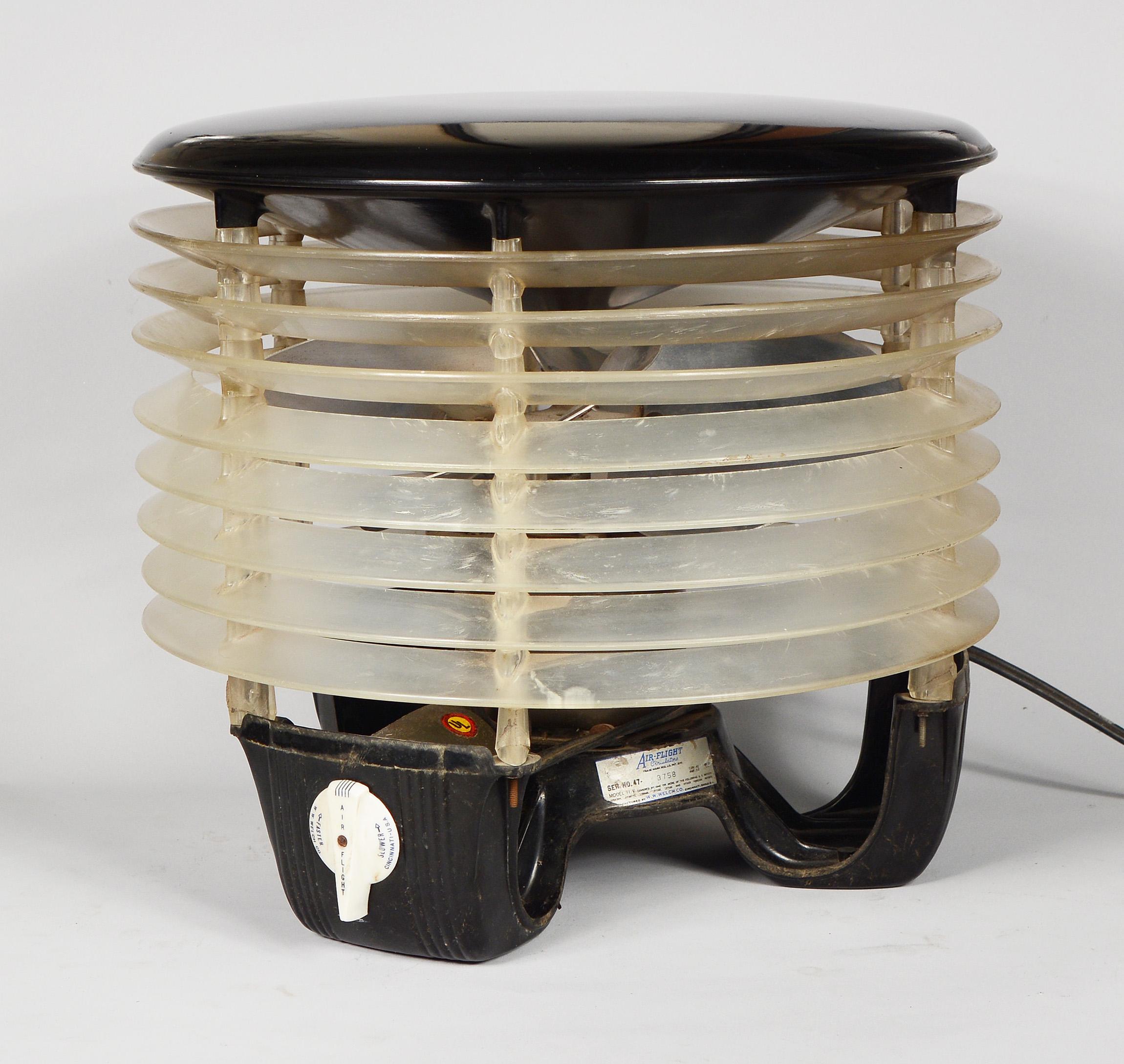 Air Flight machine age hassock fan manufactured by W. W. Welch Company. This fan has a Bakelite top and bottom with clear plastic louvers in between. The fan has two speeds and is in working condition. None of the louvers are broken but some do