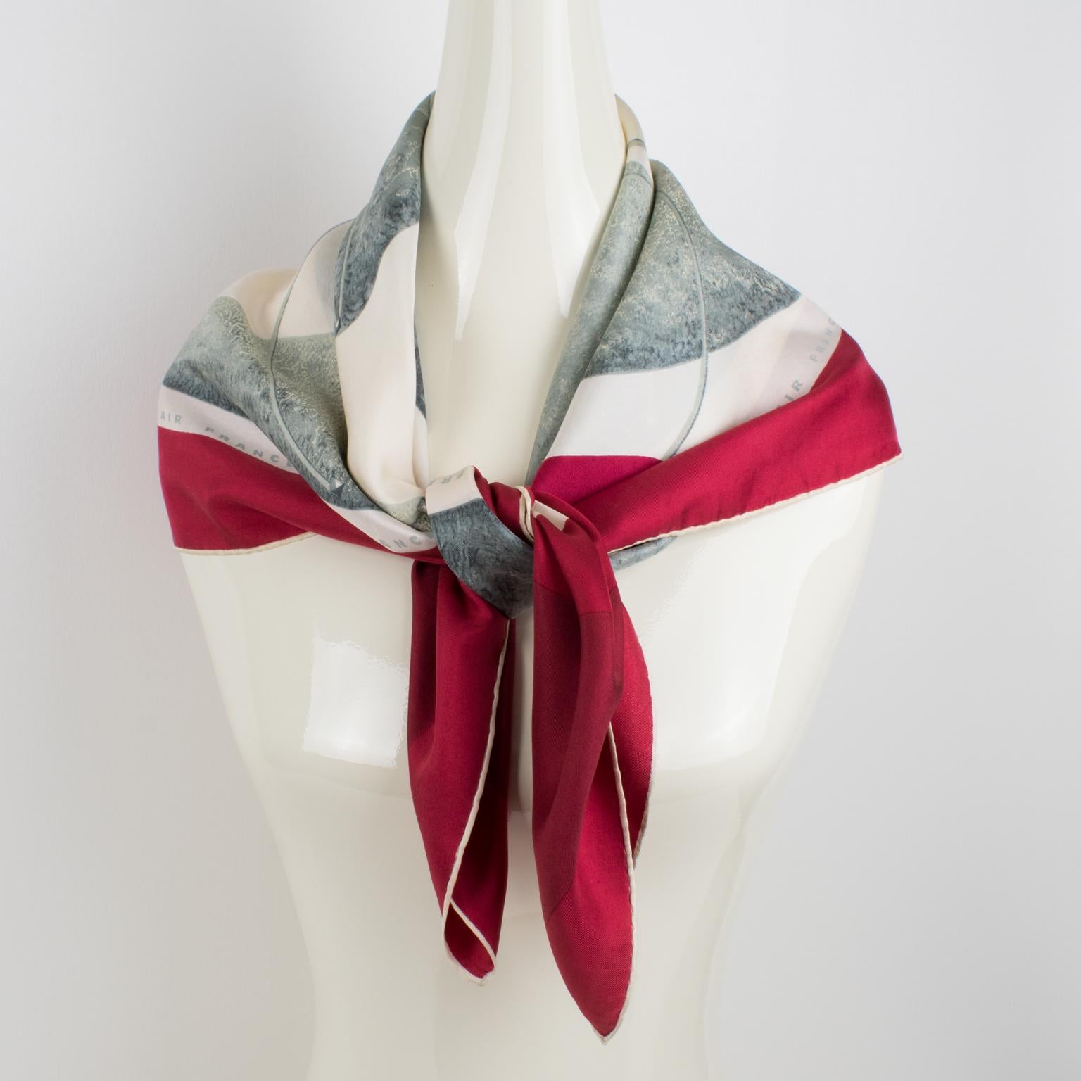 This lovely promotional Air France silk scarf has a very chic colored pattern print with an abstract design featuring a globe of the planet with stylized continents. The piece features a vibrant ruby-red border with bright gray and white colors. The