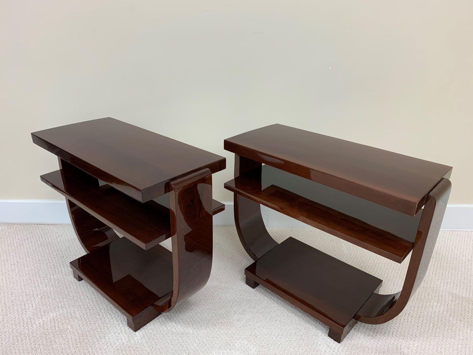 Pair of Art Deco Machine Age end tables made and retail by the Modernage Furniture Company. An elegant design with three shelves supported by a soft curving U. Perfectly restored in a walnut gloss finish. Height 22 Width 12 Length