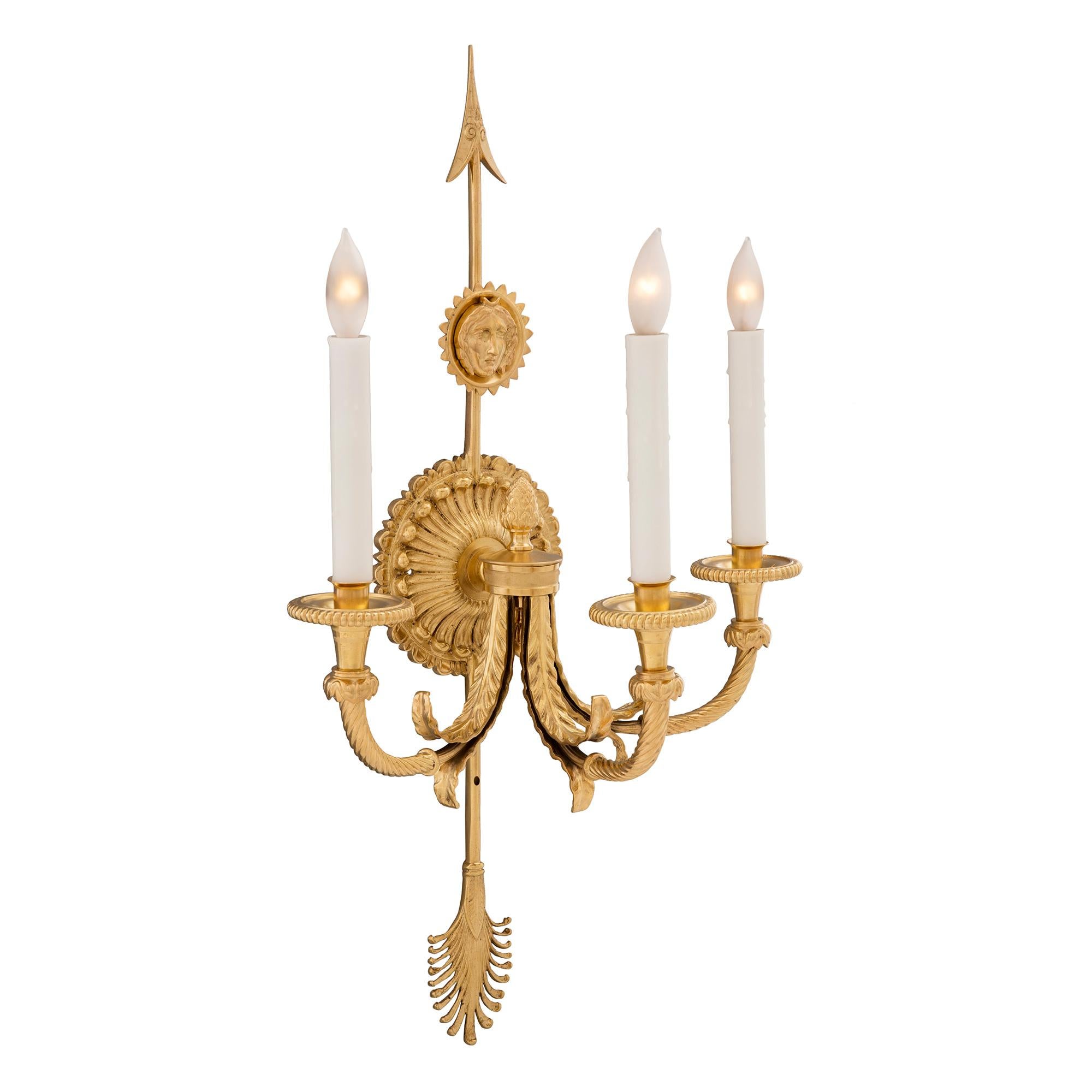 A striking pair of French 19th century neo-classical st. ormolu three arm sconces. Each sconce is centered by a beautiful bottom palmette. At the centers are most decorative circular reeded foliate reserves with acorn finials from where the three