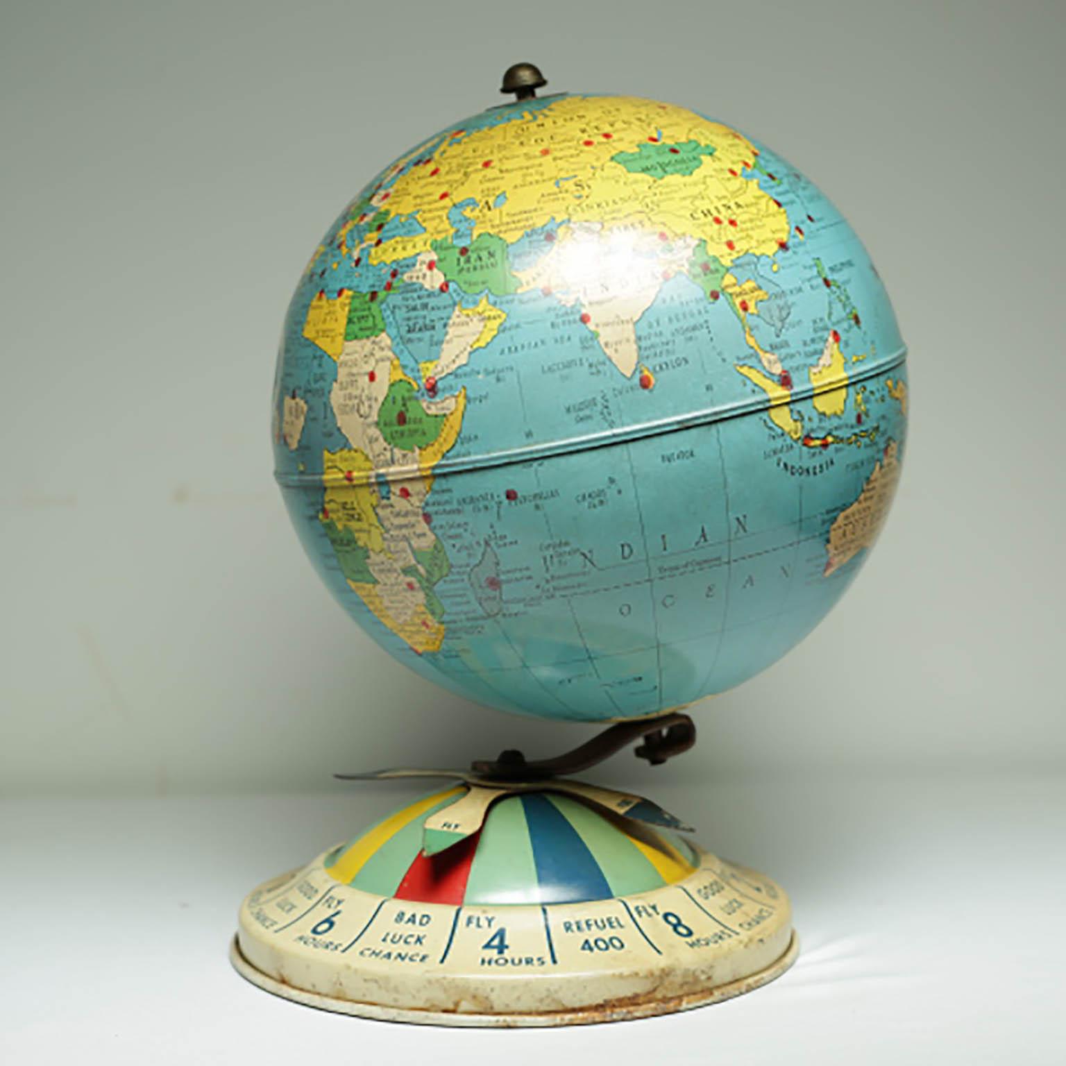 All metal globe and base with spinning dial on the base. Originally part of a air race game board that included magnetic metal planes that were placed on the red dots on the globe. 

The dial says 