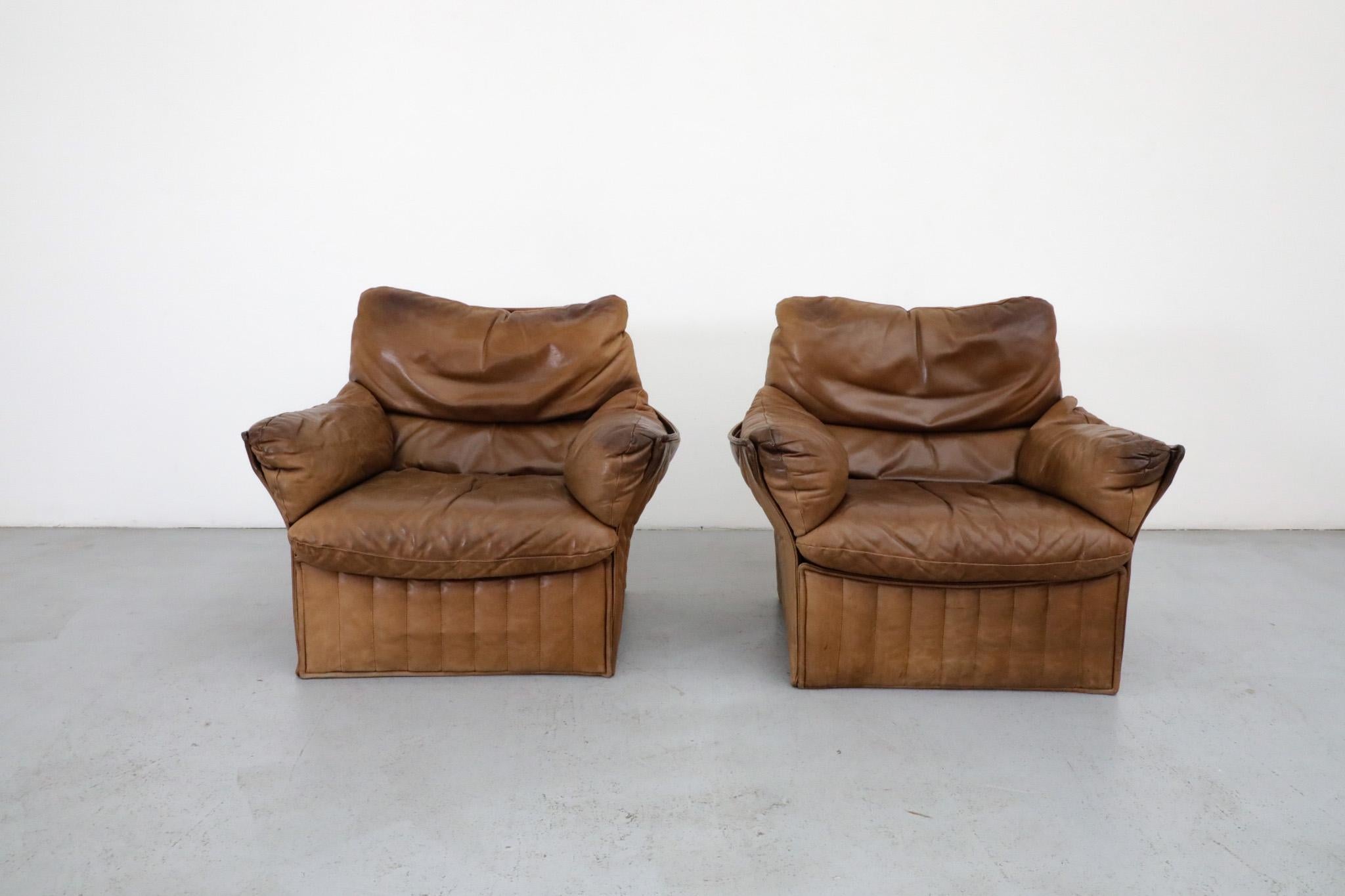 Airborne International lounge chairs in brown natural leather with excellent patina. Incredible structured ribbed and sewn back and sides provide style and flex, as well as the frame for comfy, pillowy leather cushions. In original condition with