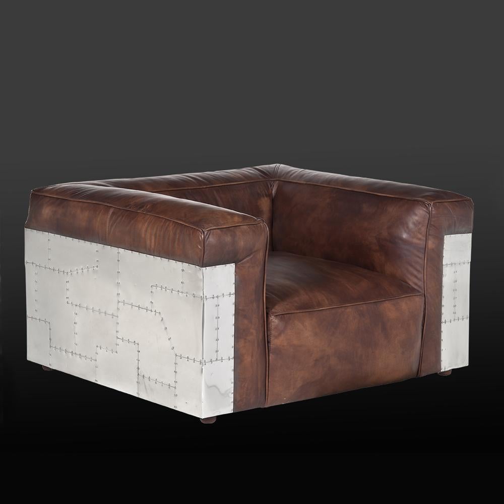 Fauteuil avion riveté revêtu de riveté poli
aluminium et structure en bois massif. Siège, dossier et 
accoudoirs rembourrés et recouverts de cuir véritable 
en finition whisky.