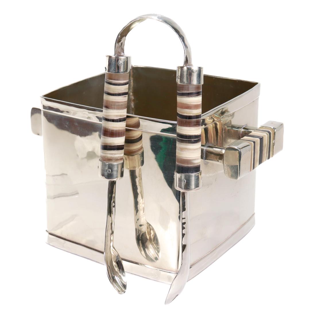 A fine Argentinian ice bucket & tongs set.

By Airedelsur.

In alpaca metal (a copper, nickel, and zinc alloy).

Both tongs and bucket have handles made of striped cow horn.

Marked to both the bucket and tongs for Airedelsur / Made in
