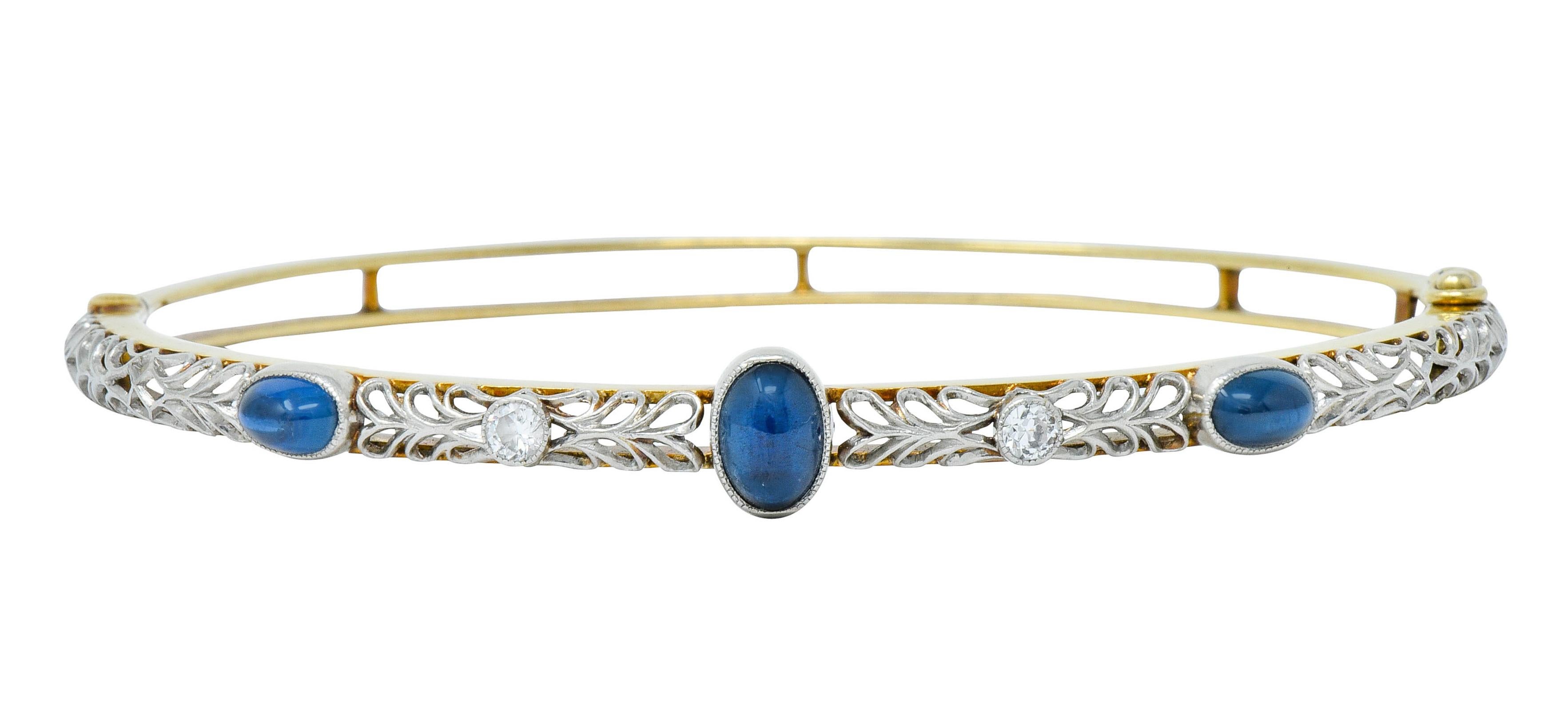 Hinged bangle bracelet with an intricately pierced platinum top featuring bezel set sapphire cabochon and transitional cut diamonds

Sapphires are oval in shape, a well-matched denim blue color, and weigh approximately 1.90 carats