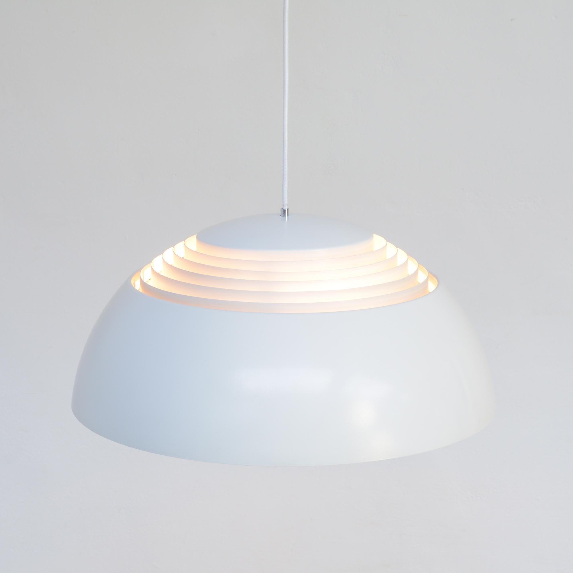 Arne Jacobsen designed the AJ Royal pendant lamp for the SAS Royal Hotel in Copenhagen in 1957. It was published by Louis Poulsen.
The metal shade is white lacquered. A white lacquered inner shade diffuses the light upwards and downwards, so this