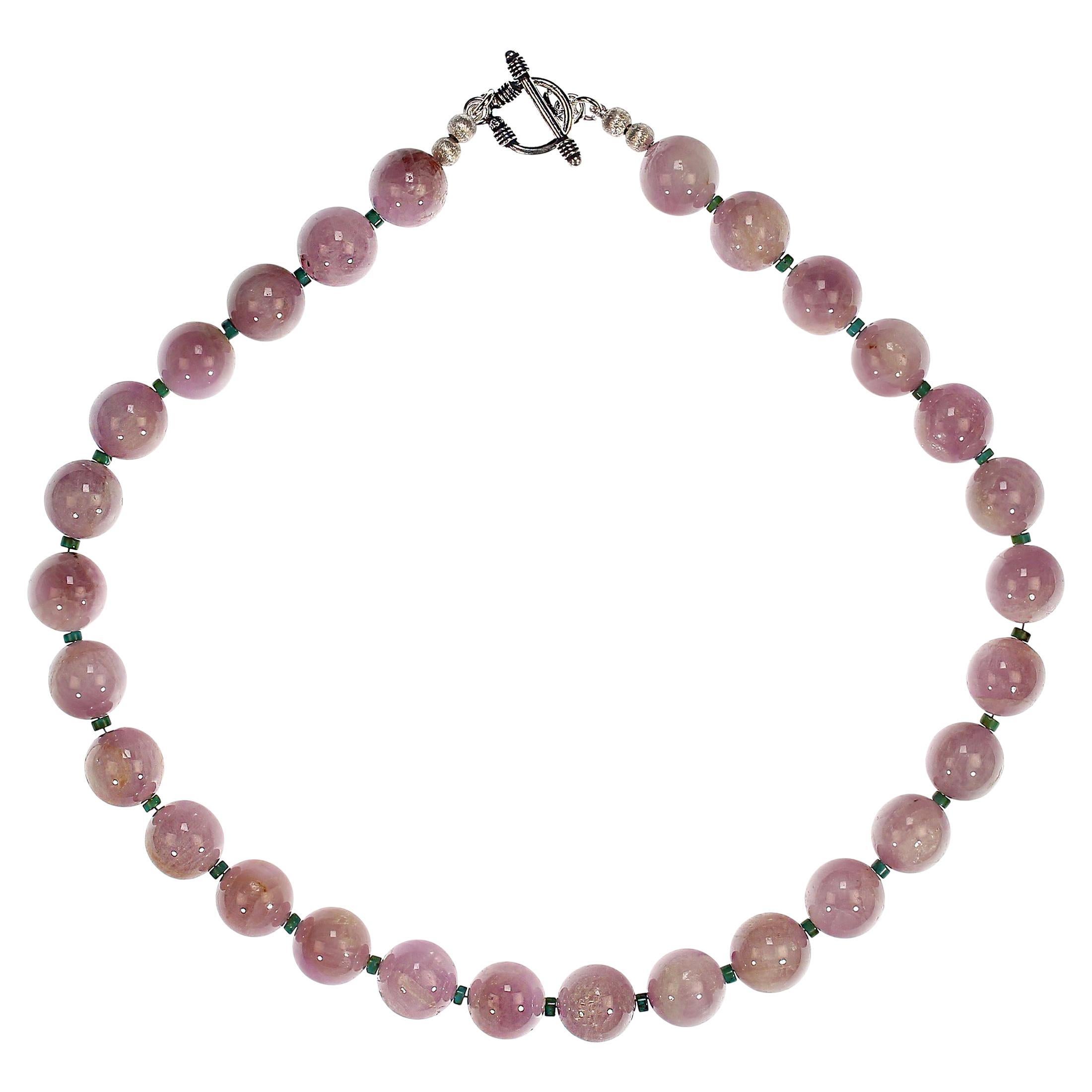 Diese atemberaubende 20-Zoll-Kunzit-Halskette in leuchtendem Mauve ist eine anmutige Verschmelzung von Raffinesse und Charme. Sein Herzstück sind hochglanzpolierte 14-mm-Kunzitperlen, die in einem warmen, durchscheinenden Mauve schimmern und bei