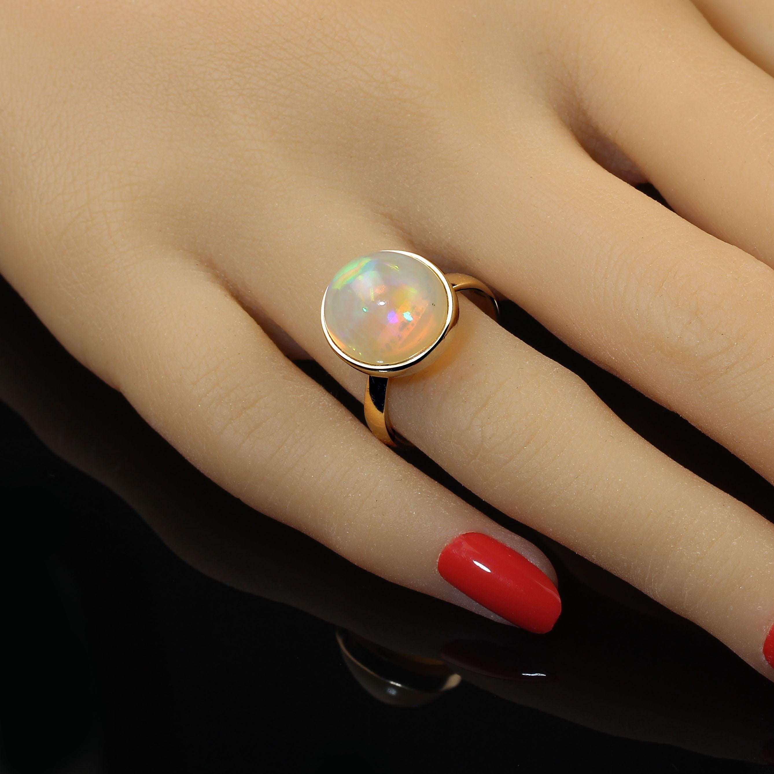 Creamy round opal with flashes of green and blue set in a handmade 18KT rich yellow gold setting. This is from our favorite craftsman in Belo Horizonte, Minas Gerais, Brazil. This lovely opal cabochon is bezel set in a simple sizable 7 ring.  No