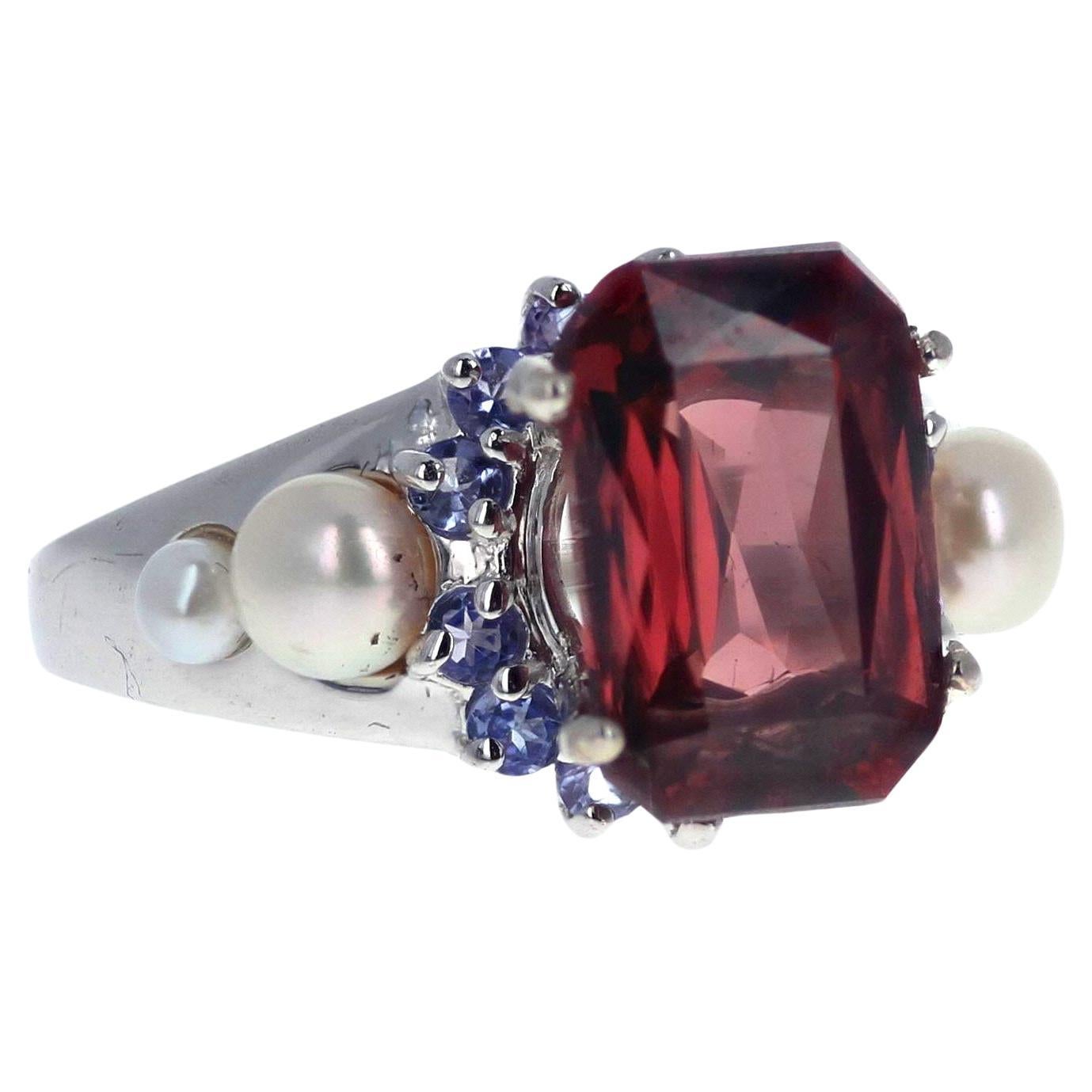 This 7.2 Carat glittering natural red Zircon measures 12 mm x 8 mm and is set in a Sterling Silver ring enhanced with blue Sapphires and white Pearls. The ring is size 7 (sizable). There are no eye visible inclusions in this magnificent rare Zircon.