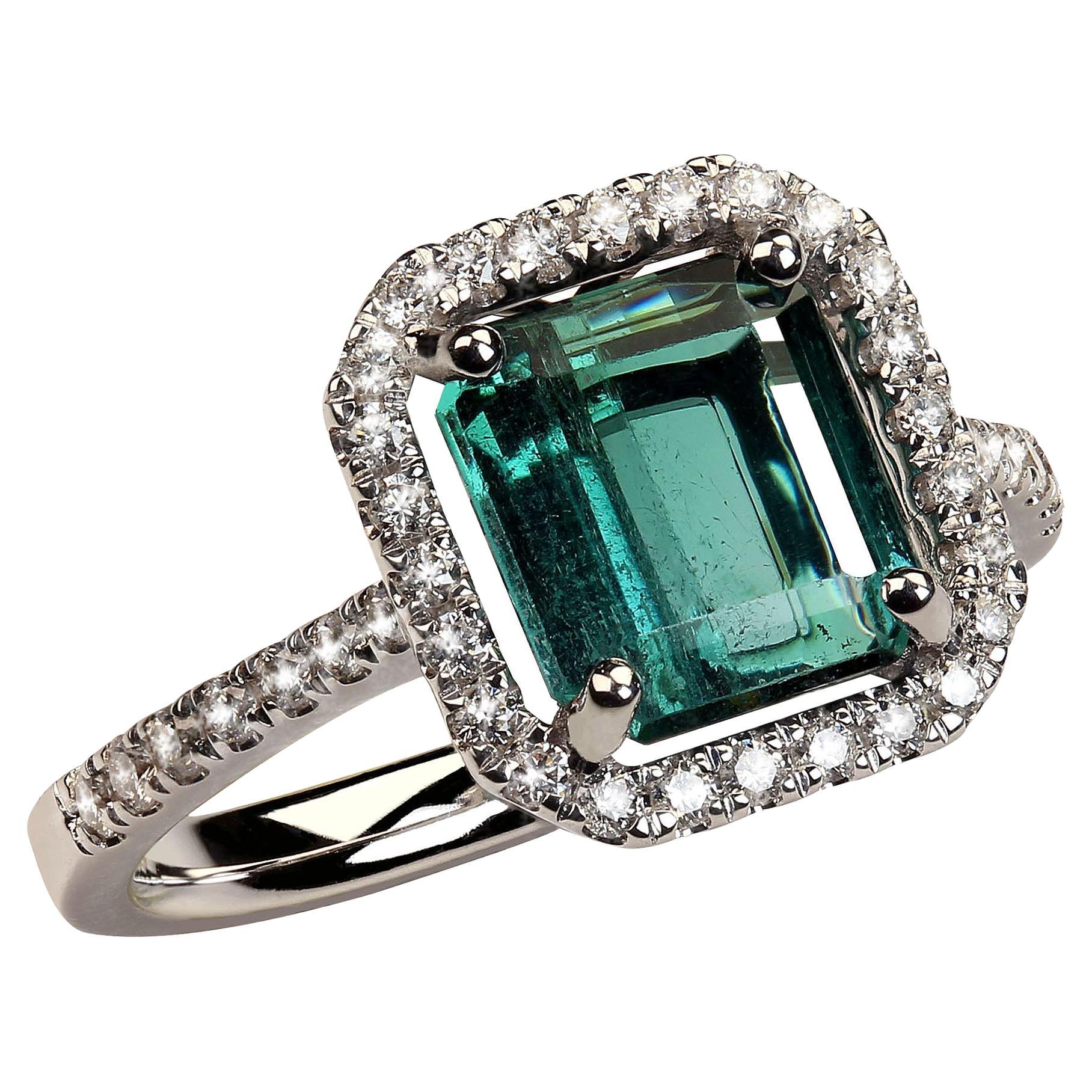 Lovely Brazilian green Tourmaline and Diamond Dinner Ring.  This gleaming green Tourmaline is enhanced with a halo of  diamonds with more diamonds gracing the shank. The emerald cut bluish green Tourmaline is 8.25 x 7.5 MM and est 2 carats.  The