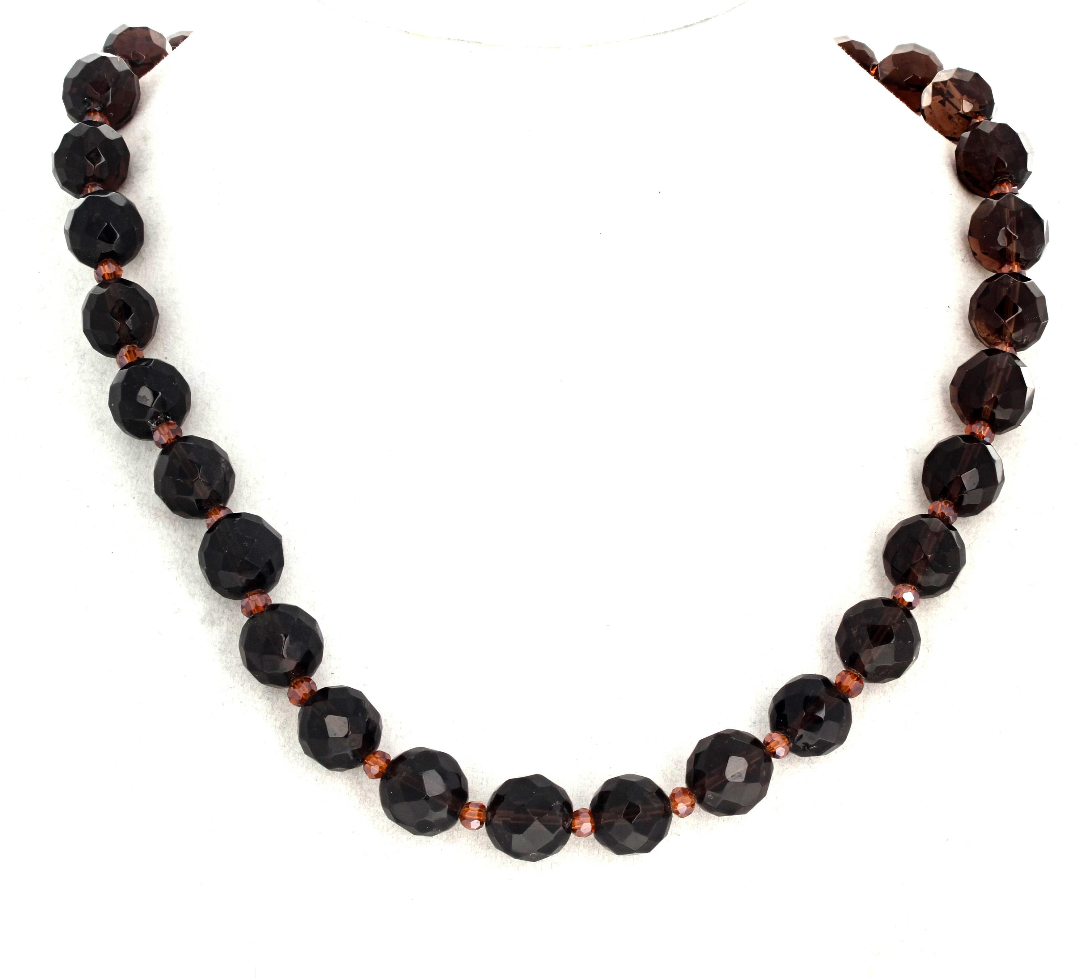 These fascinating natural Smoky Quartz are gem cut to glittering in the light in this 19 inch long necklace. They are 11mm and are enhanced by tiny glittering orangy gem cut crystals.  The clasp is an easy to use hook clasp.  