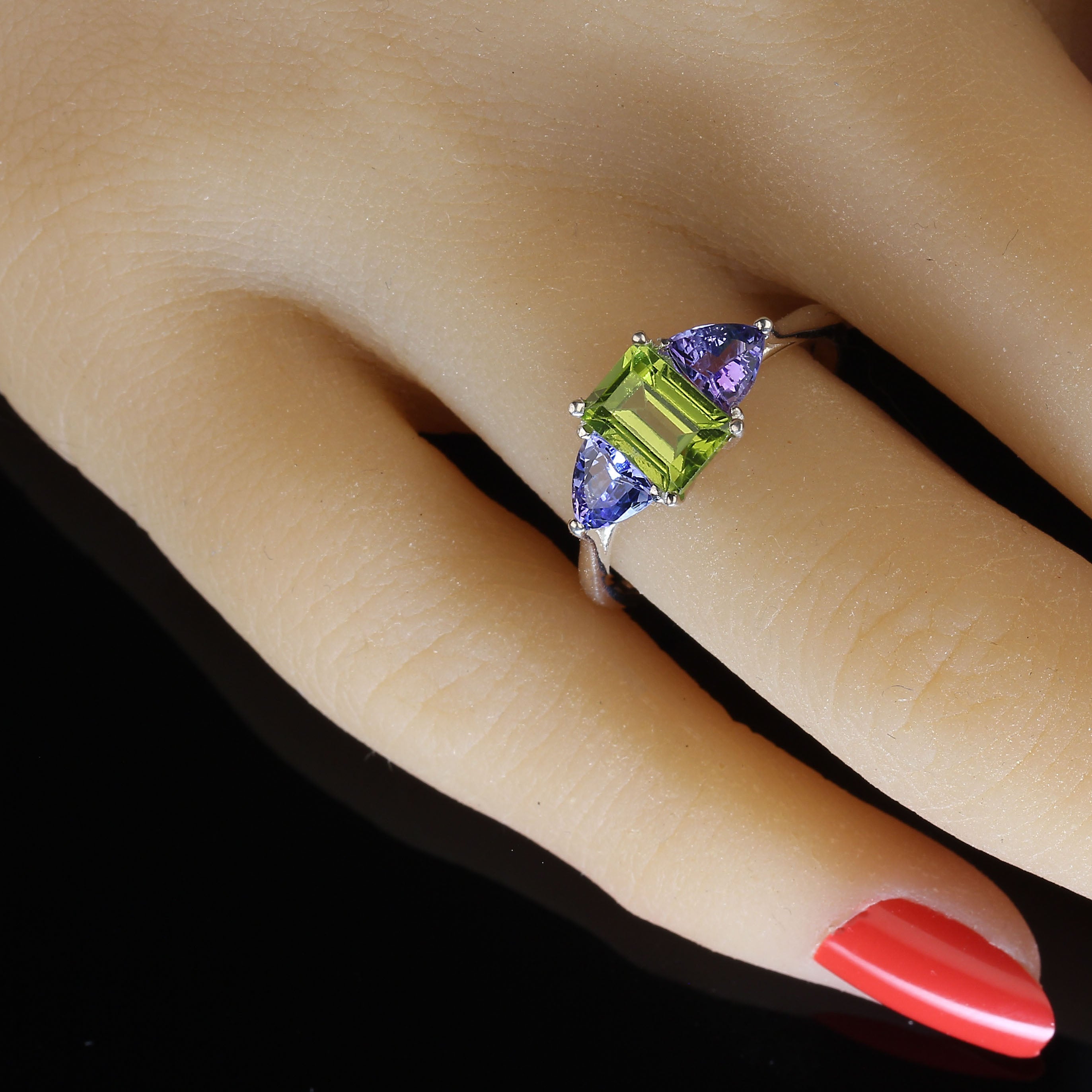 Ravissante bague de péridot scintillant de taille émeraude, accentuée par des triangles de tanzanites scintillantes. Portez ces bijoux avec tout et appréciez la façon dont le vert et le violet se marient avec toute votre garde-robe.  Le péridot de